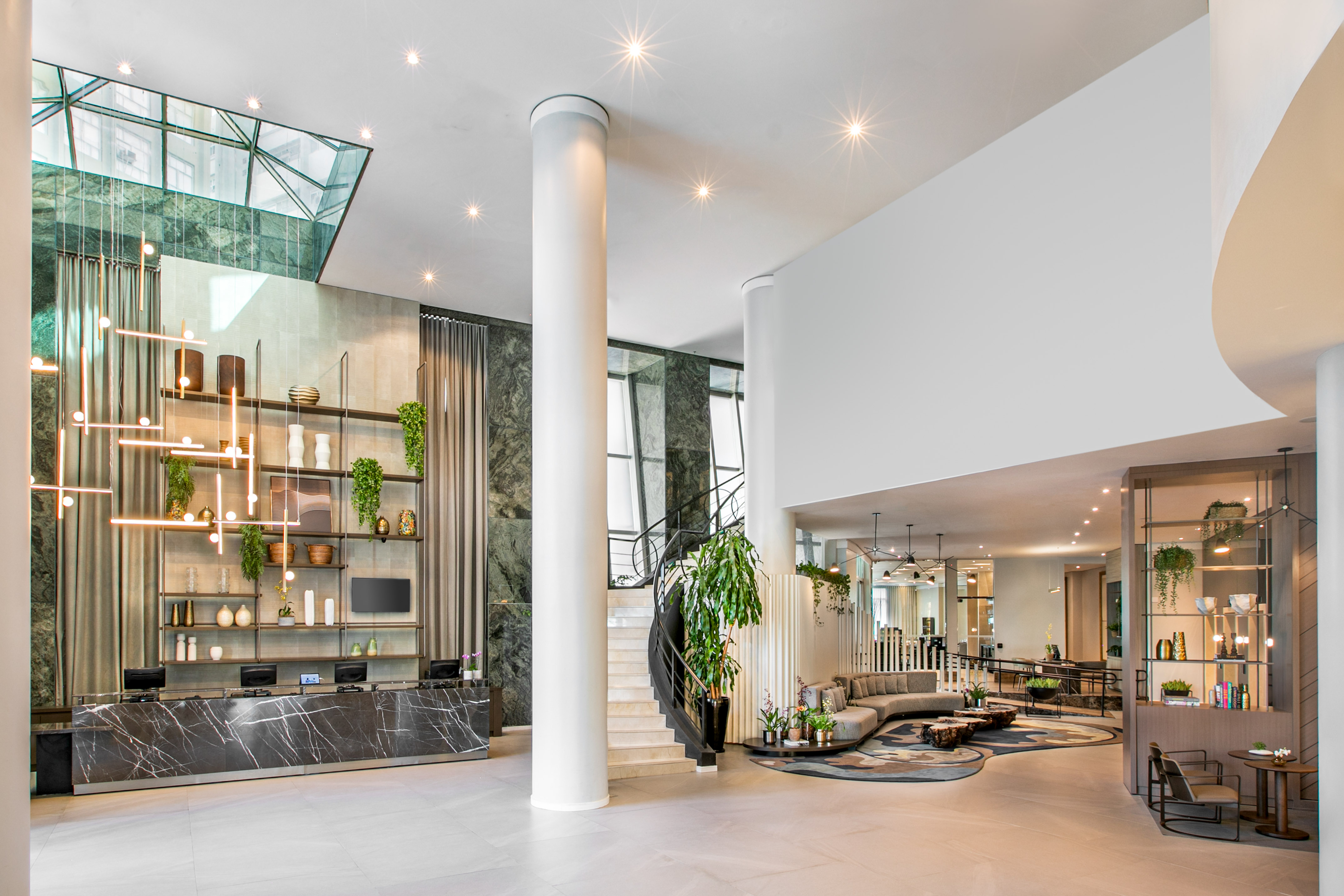 Luxury hotel lobby with marble reception, spiral stairs, and lounge area.