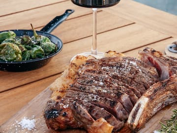 a steak on a cutting board next to a glass of wine