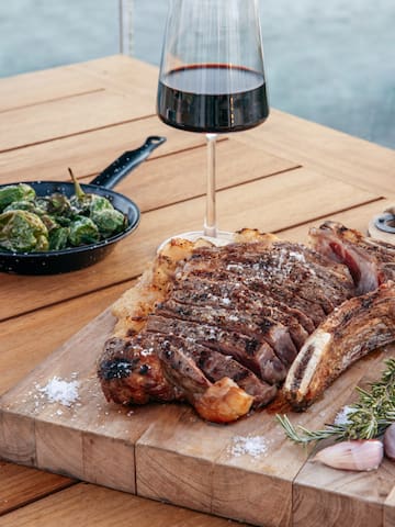 a steak on a cutting board next to a glass of wine