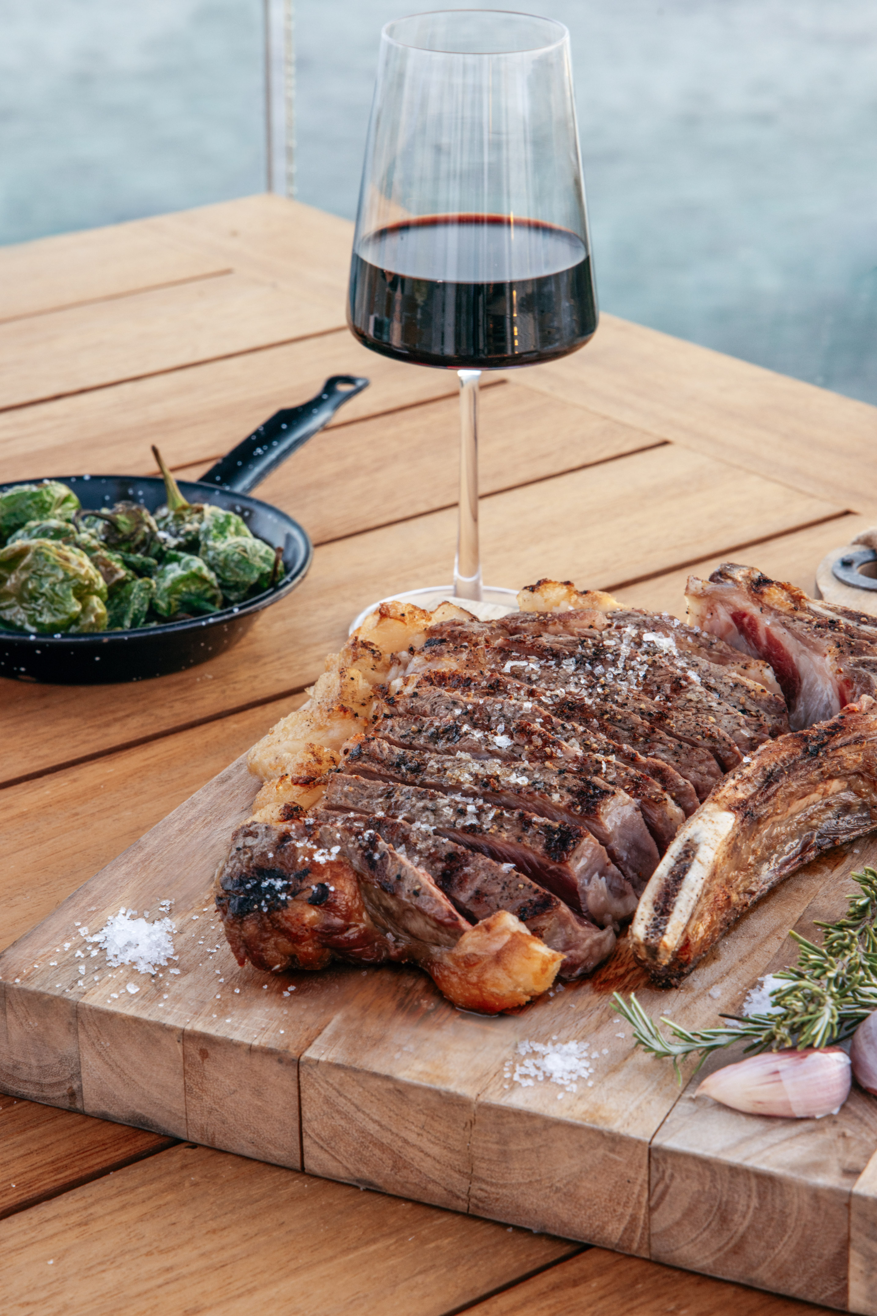 a steak on a cutting board next to a glass of wine