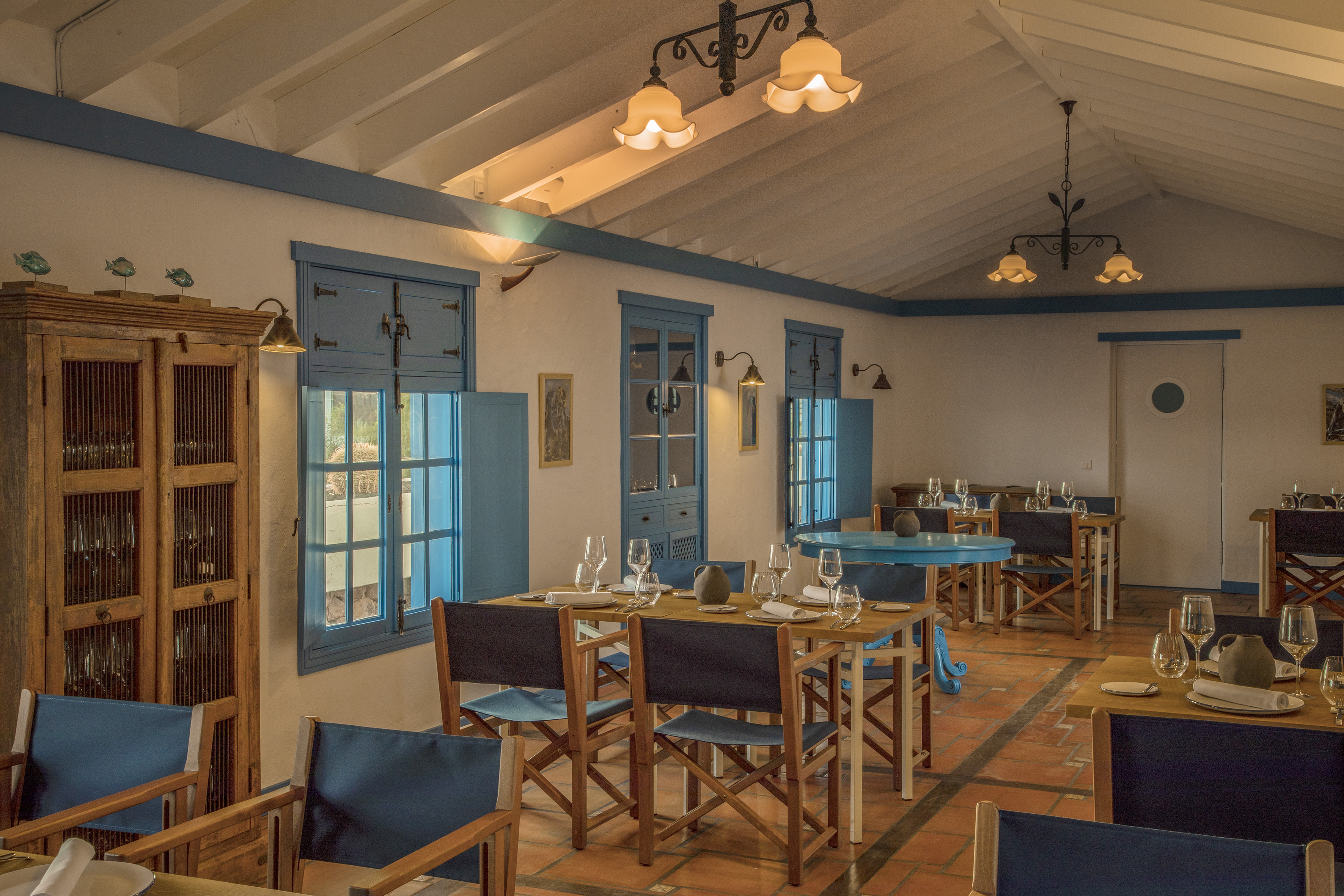 Blue and white Mediterranean restaurant dining room with set tables.