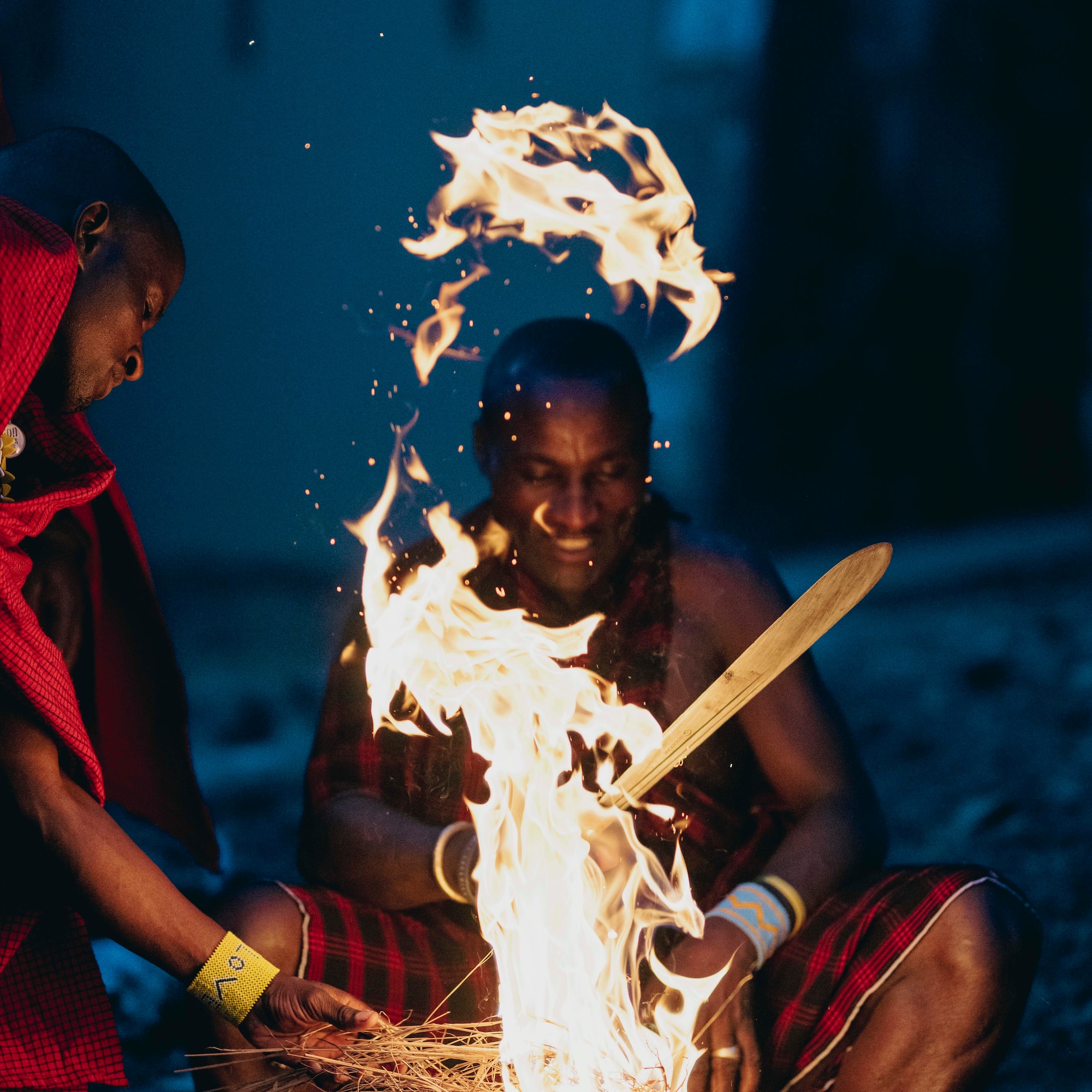 a group of men sitting around a fire