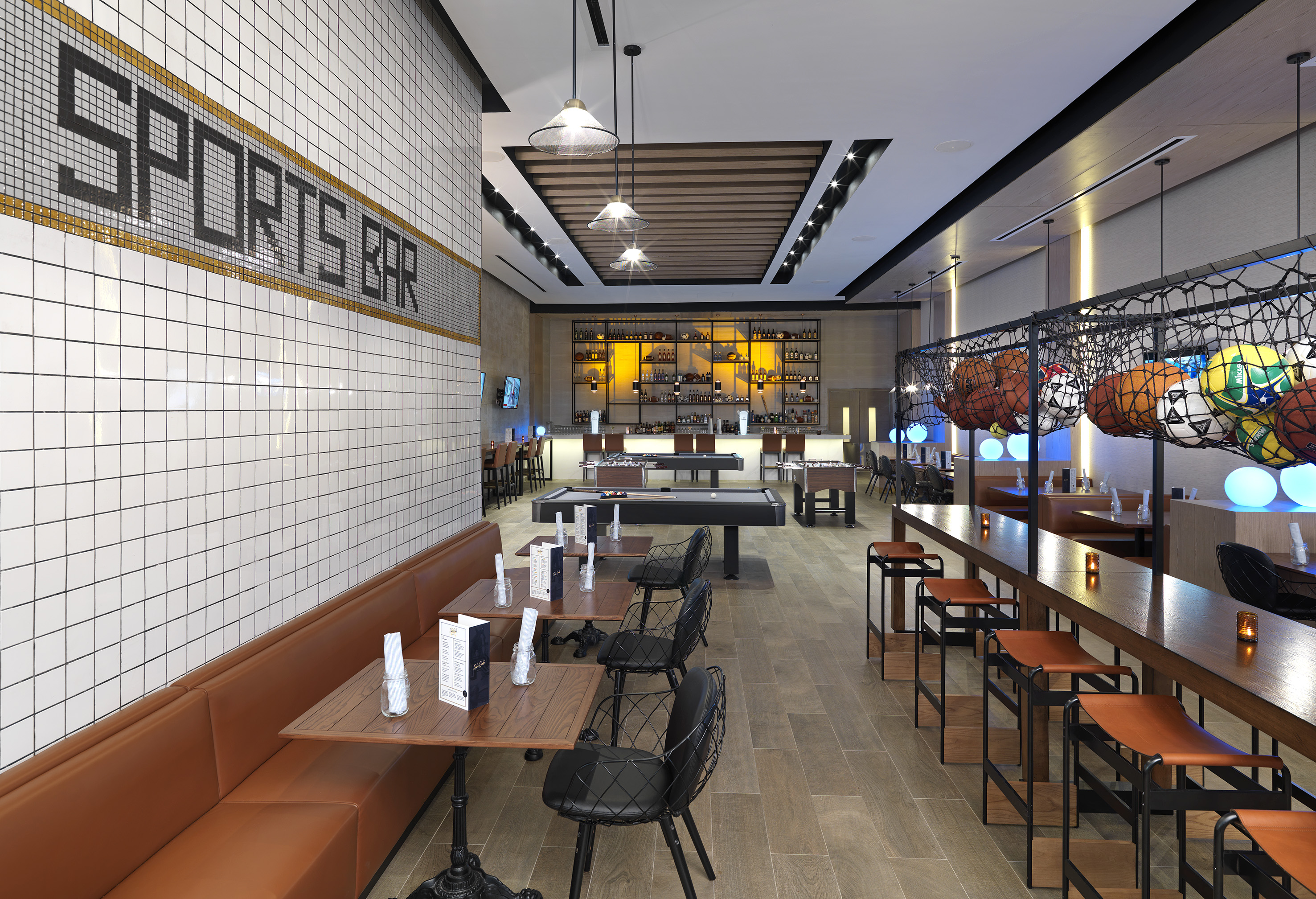 Modern sports bar with pool, foosball tables, full bar & seating.