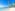 Tropical beach with palm trees, blue water, white sand, and thatched bungalows.