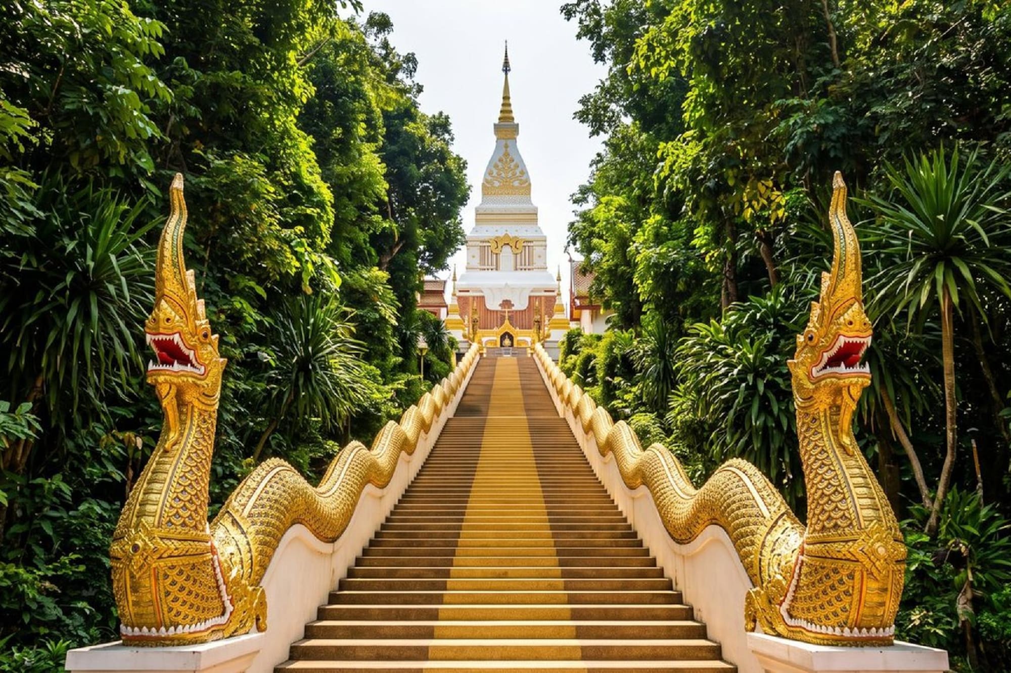 Golden Naga-flanked stairs ascend to a white stupa amidst green trees.