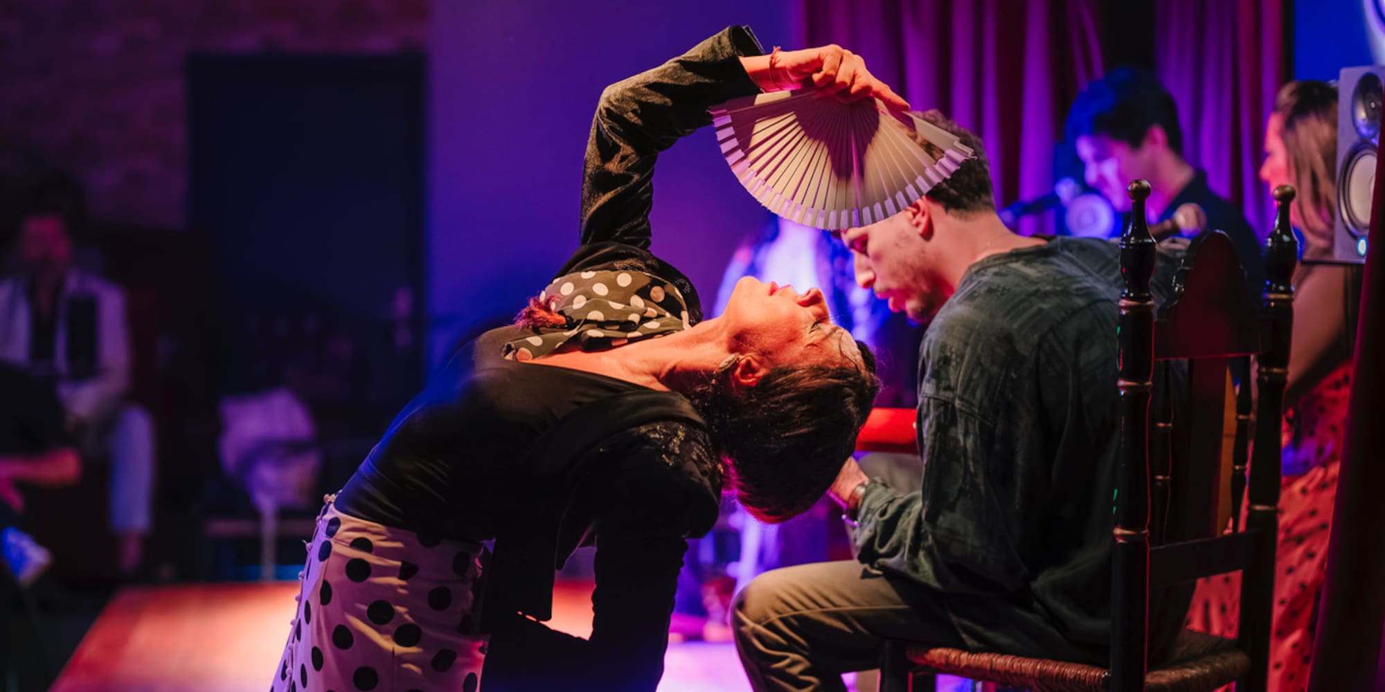 a woman holding a fan over a man's head