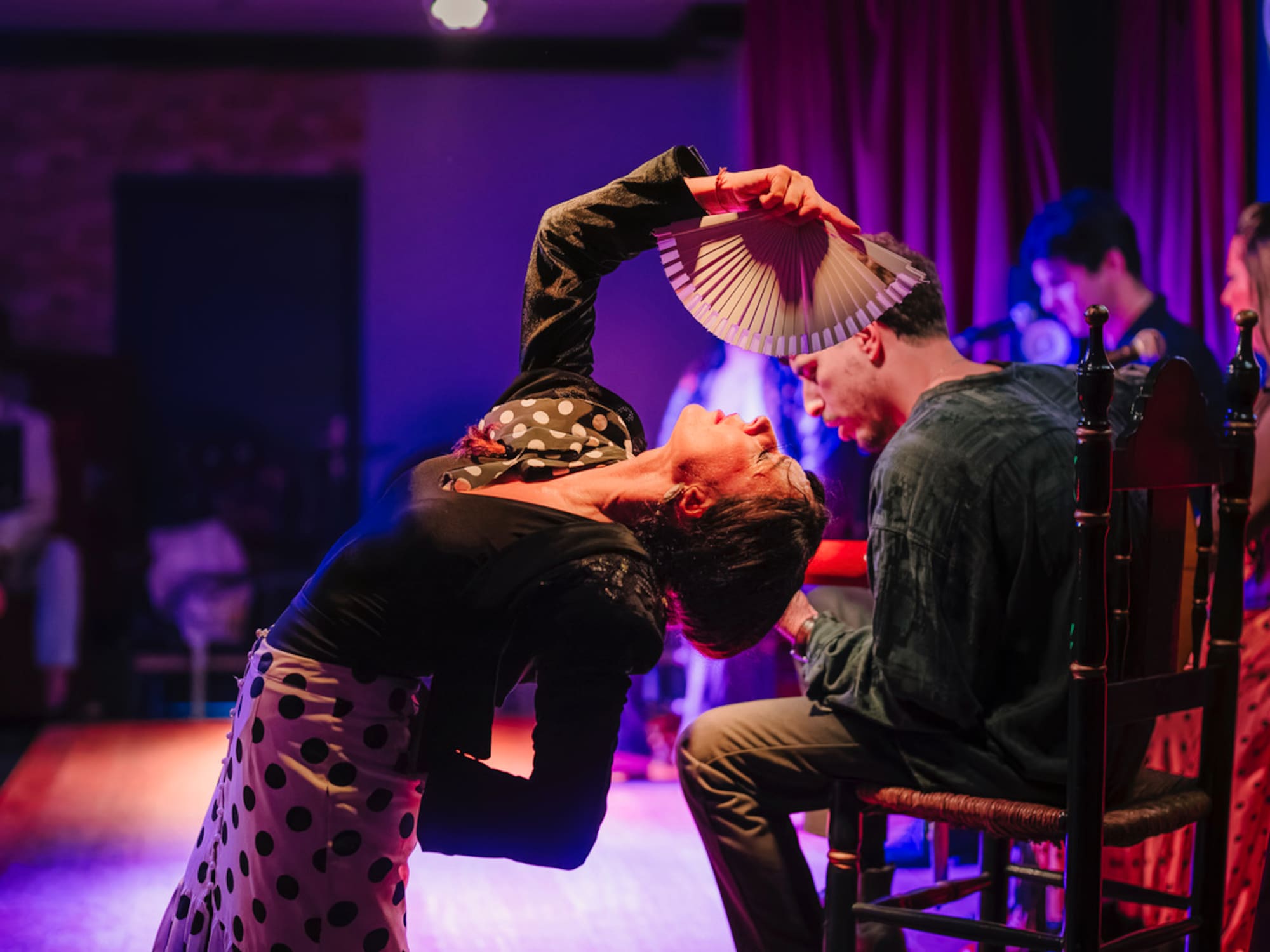 a woman holding a fan over a man's head