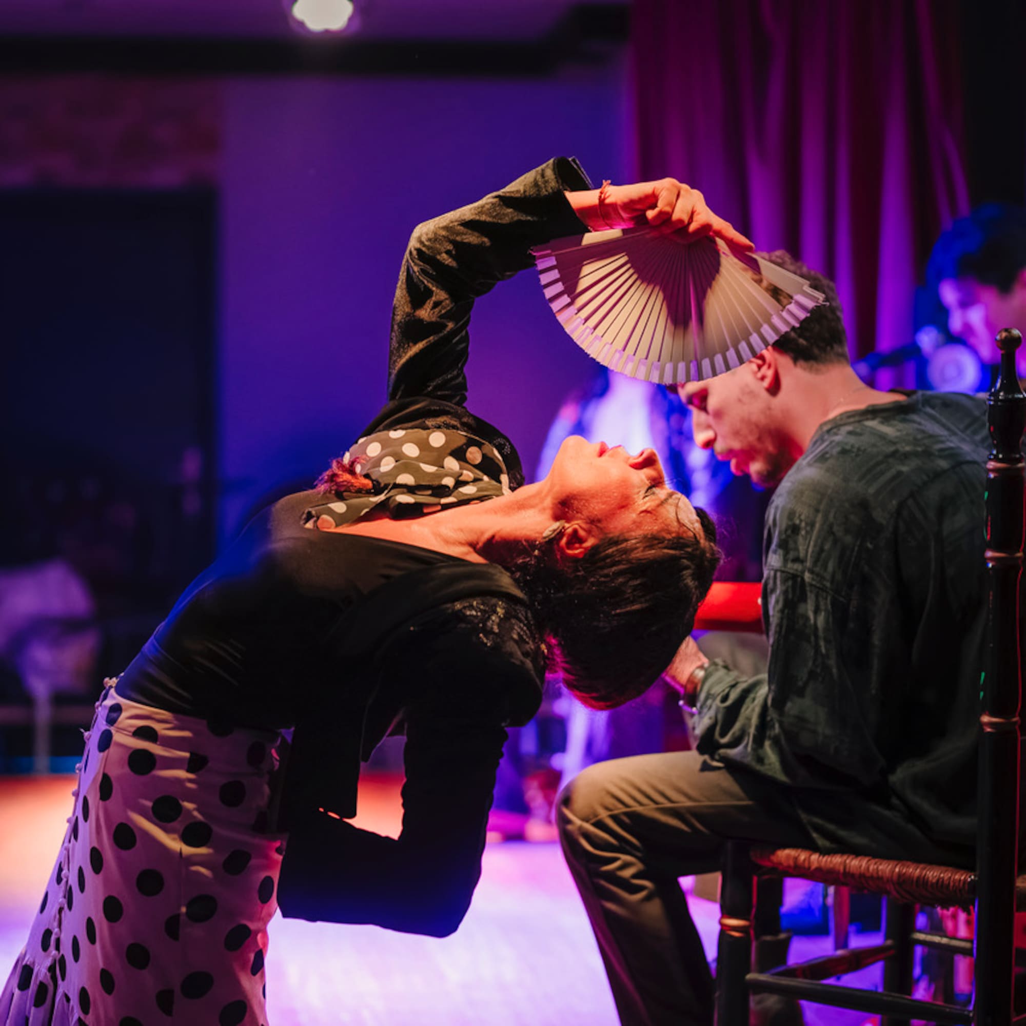 a woman holding a fan over a man's head