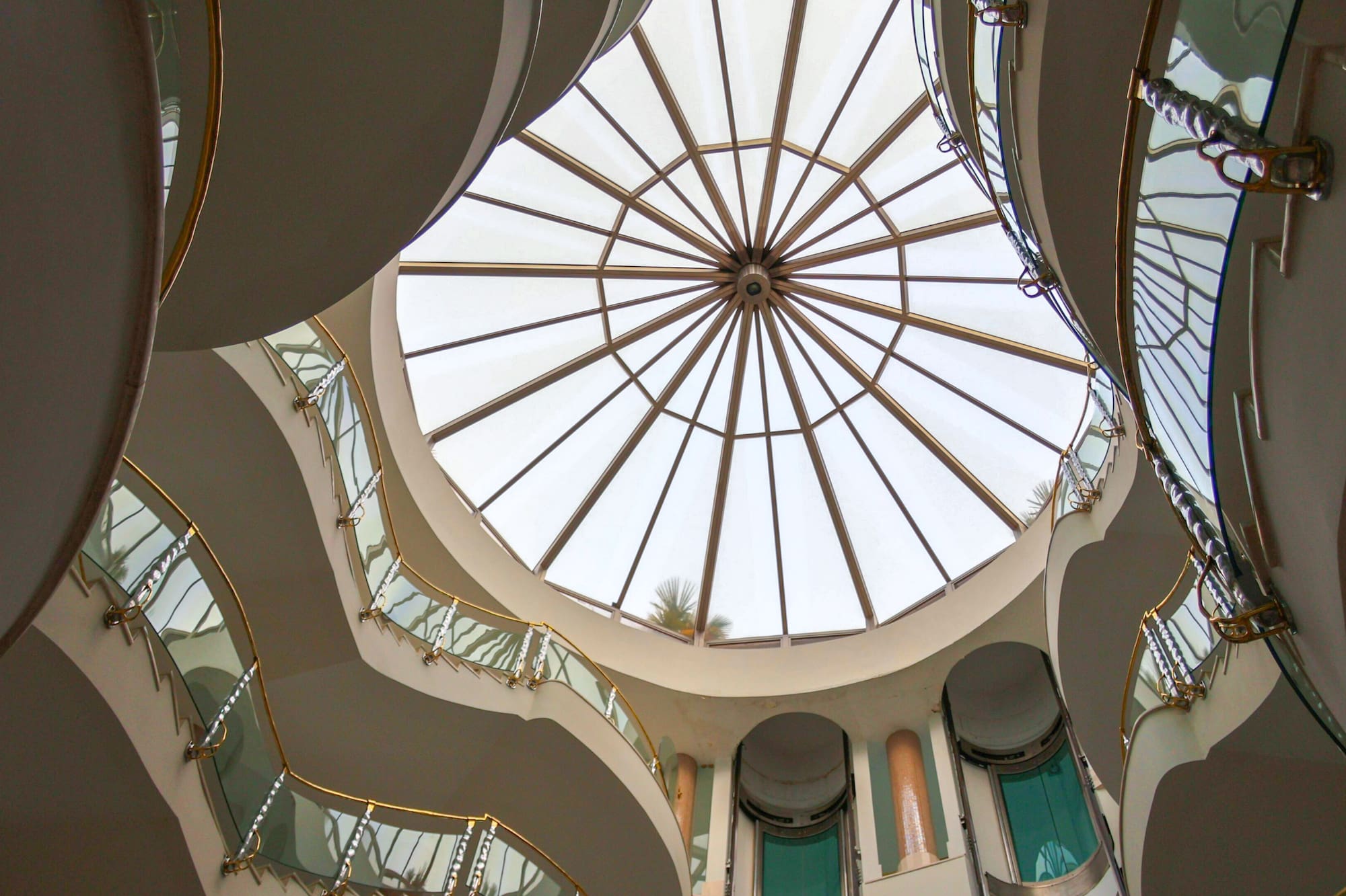 Modern atrium with circular glass dome and curved golden balconies.