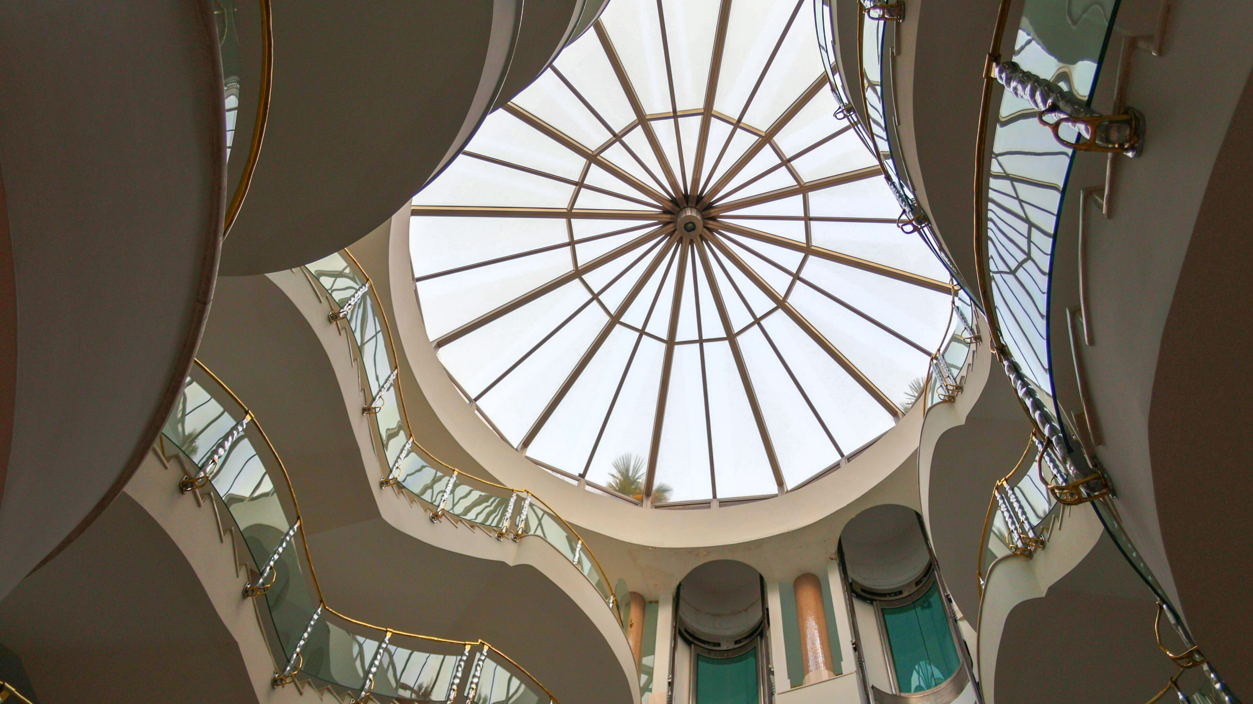 Modern atrium with circular glass dome and curved golden balconies.
