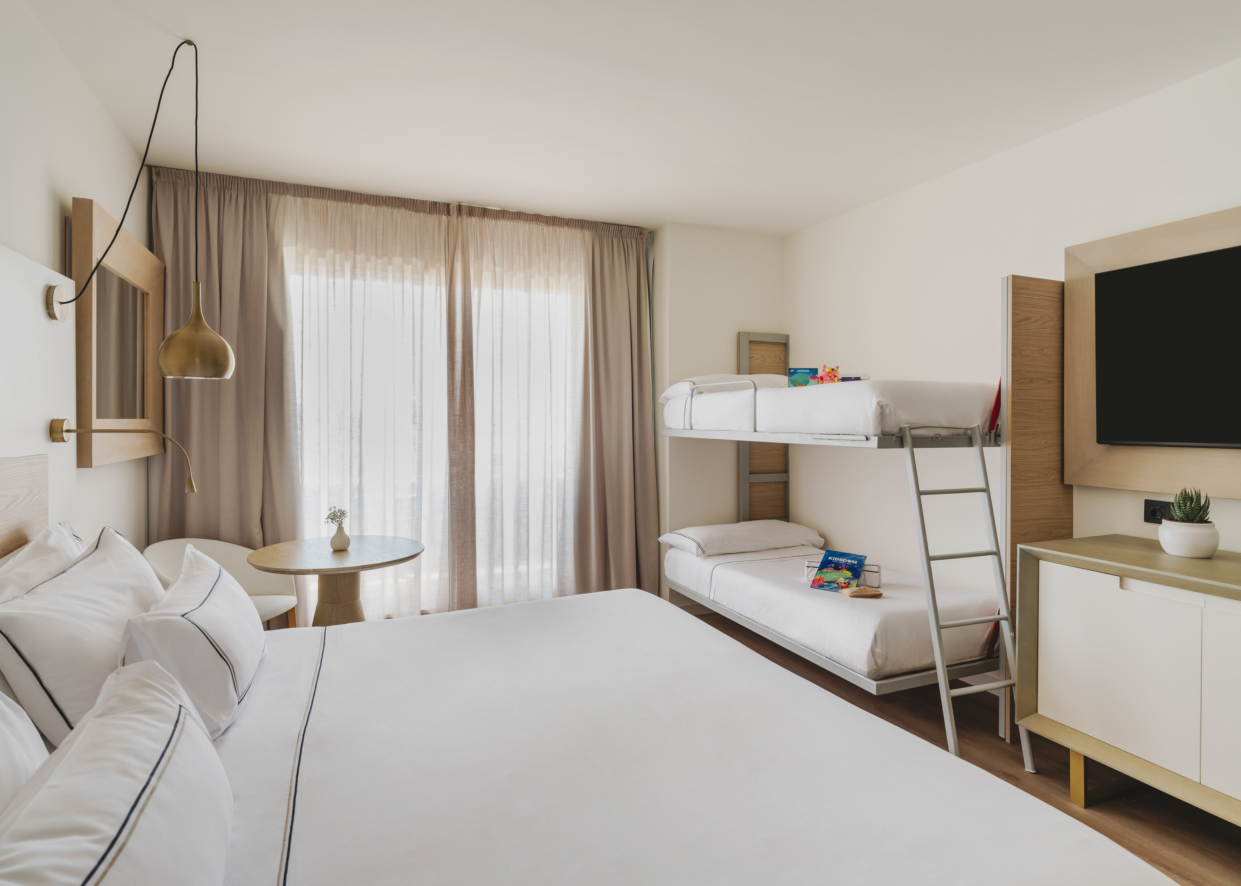 Habitación de hotel familiar moderna con cama doble y litera, ideal para vacaciones.