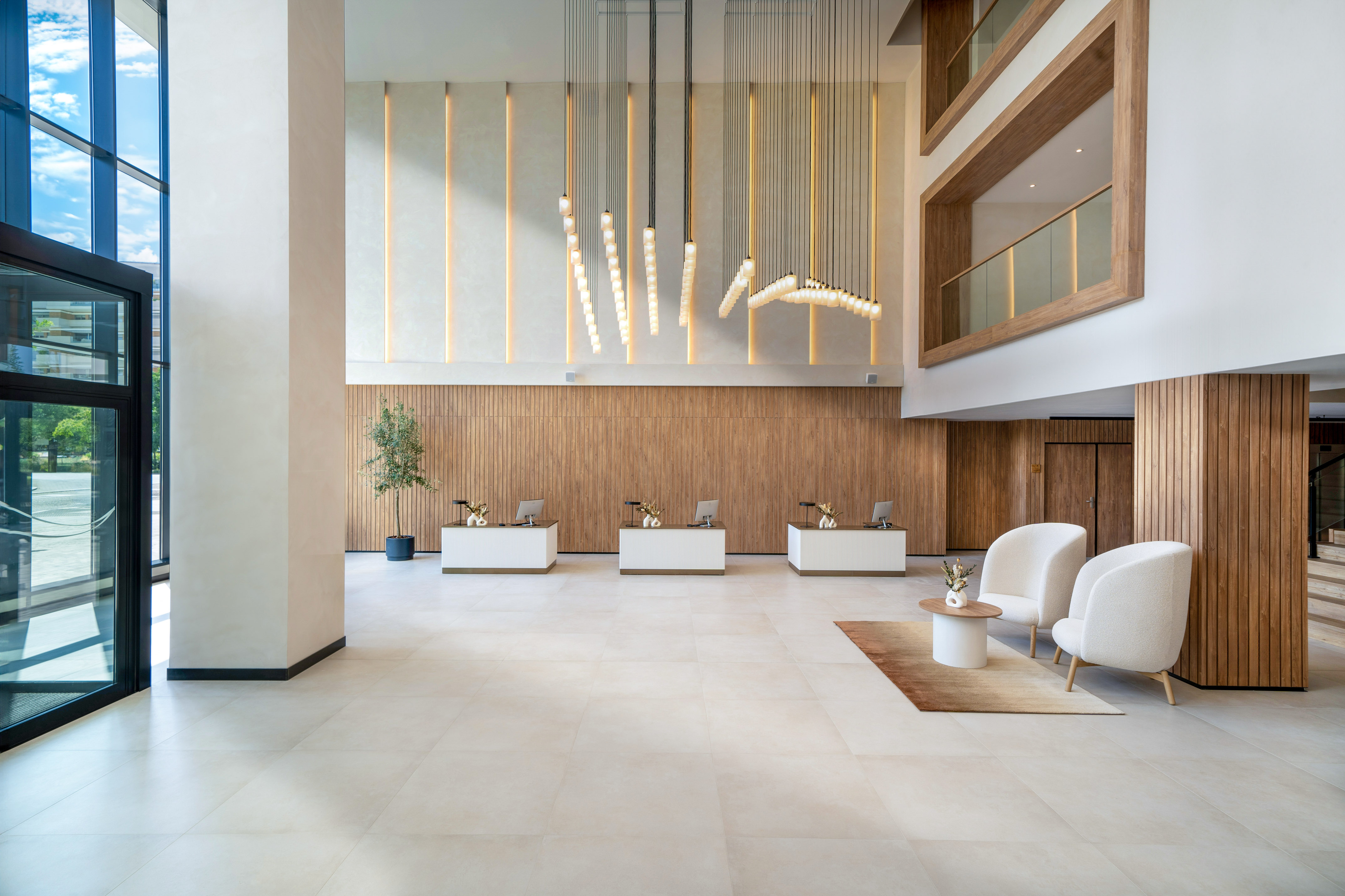 Modern hotel lobby with three front desks, wood paneling, and contemporary lighting.