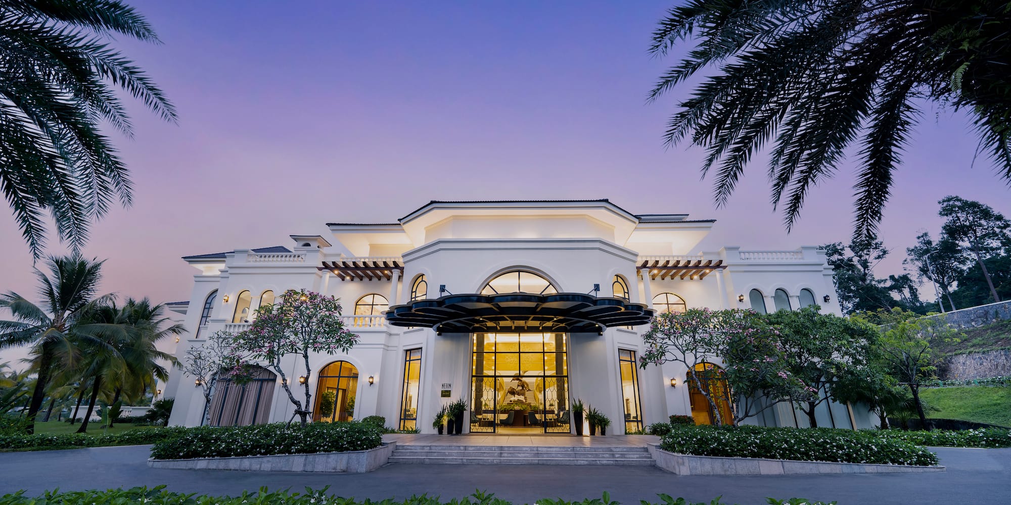 a large white building with trees and bushes