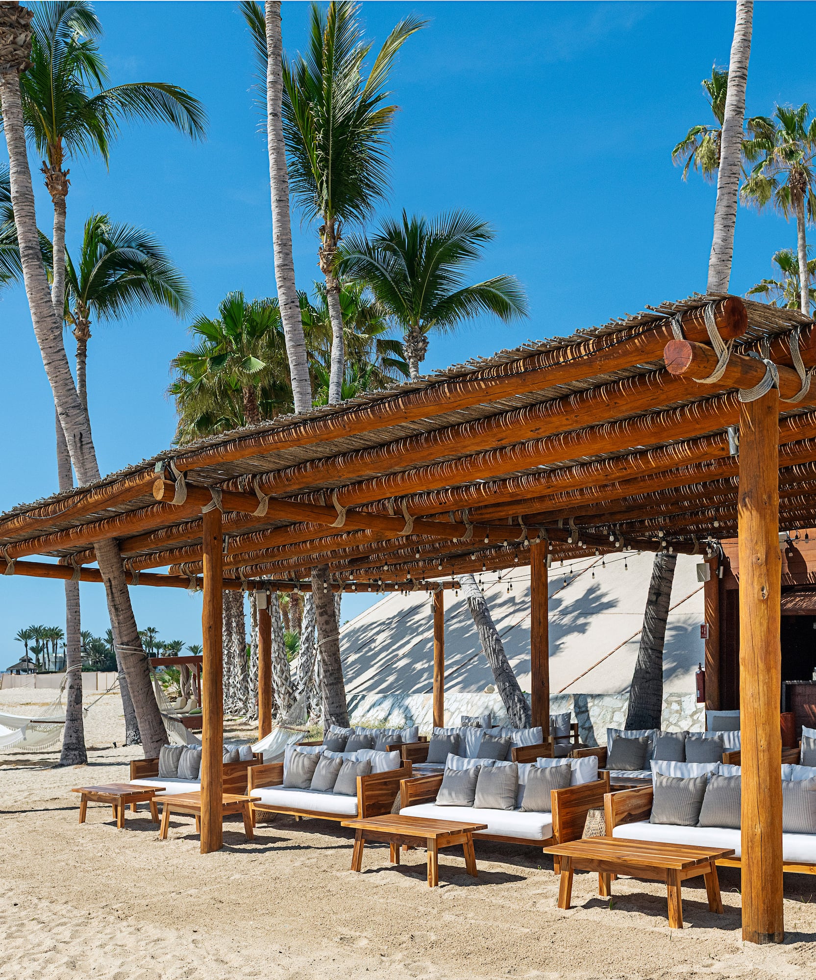 a wooden structure with a covered area with chairs and a bar on a beach