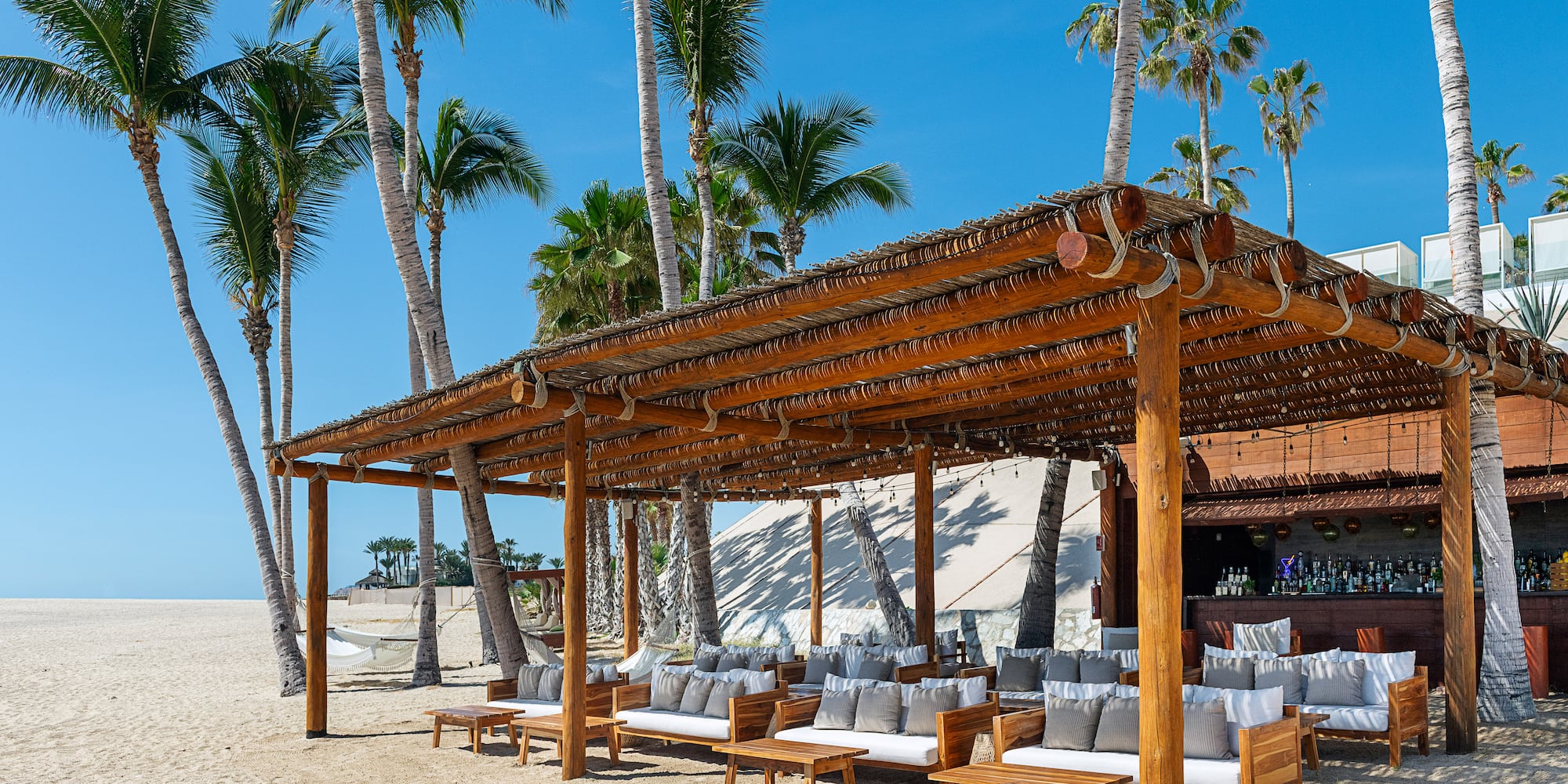a wooden structure with a covered area with chairs and a bar on a beach