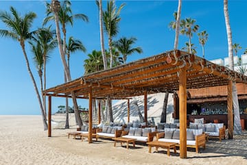 a wooden structure with a covered area with chairs and a bar on a beach