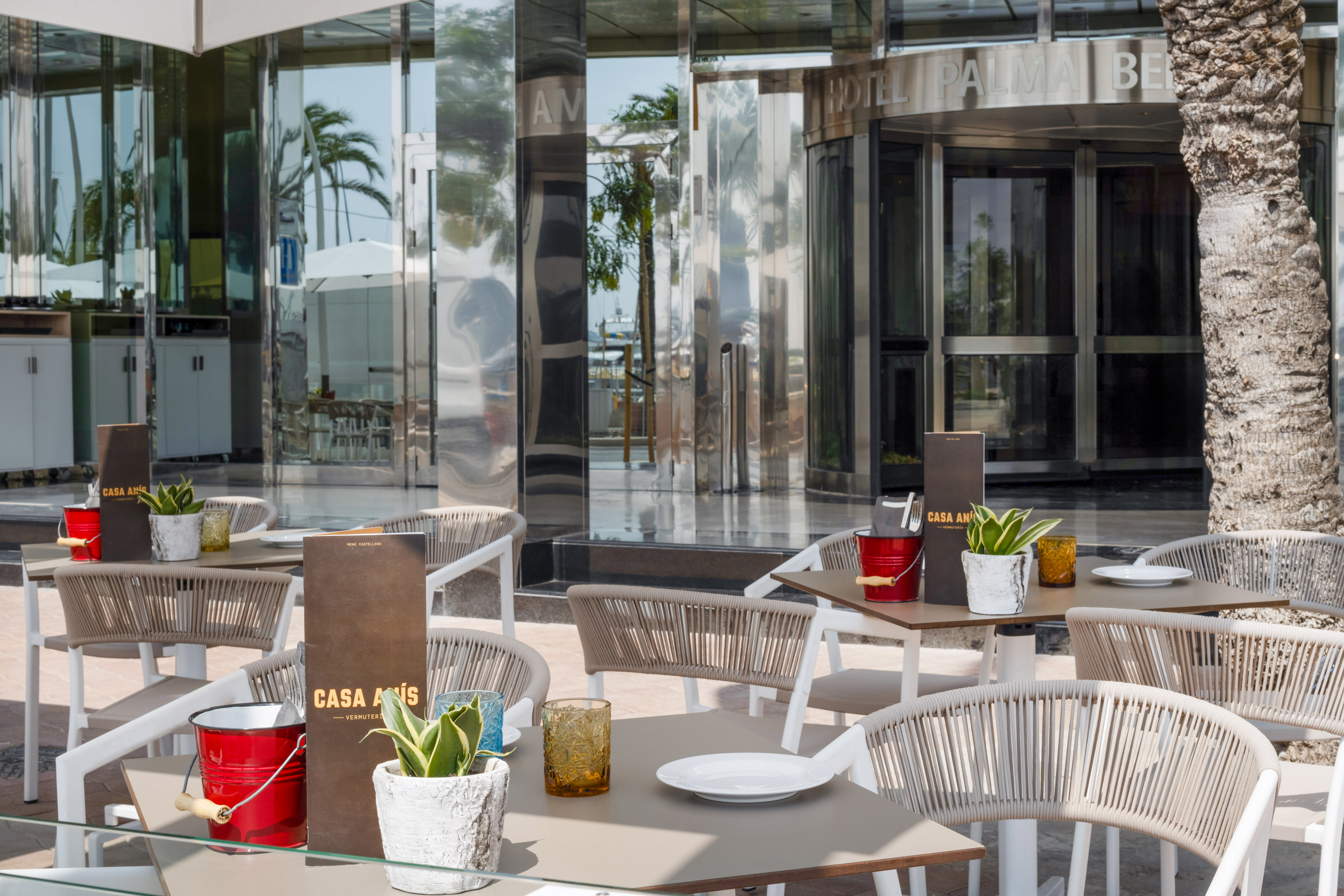 Modern outdoor patio dining at Casa Anís restaurant, reflecting a hotel entrance.