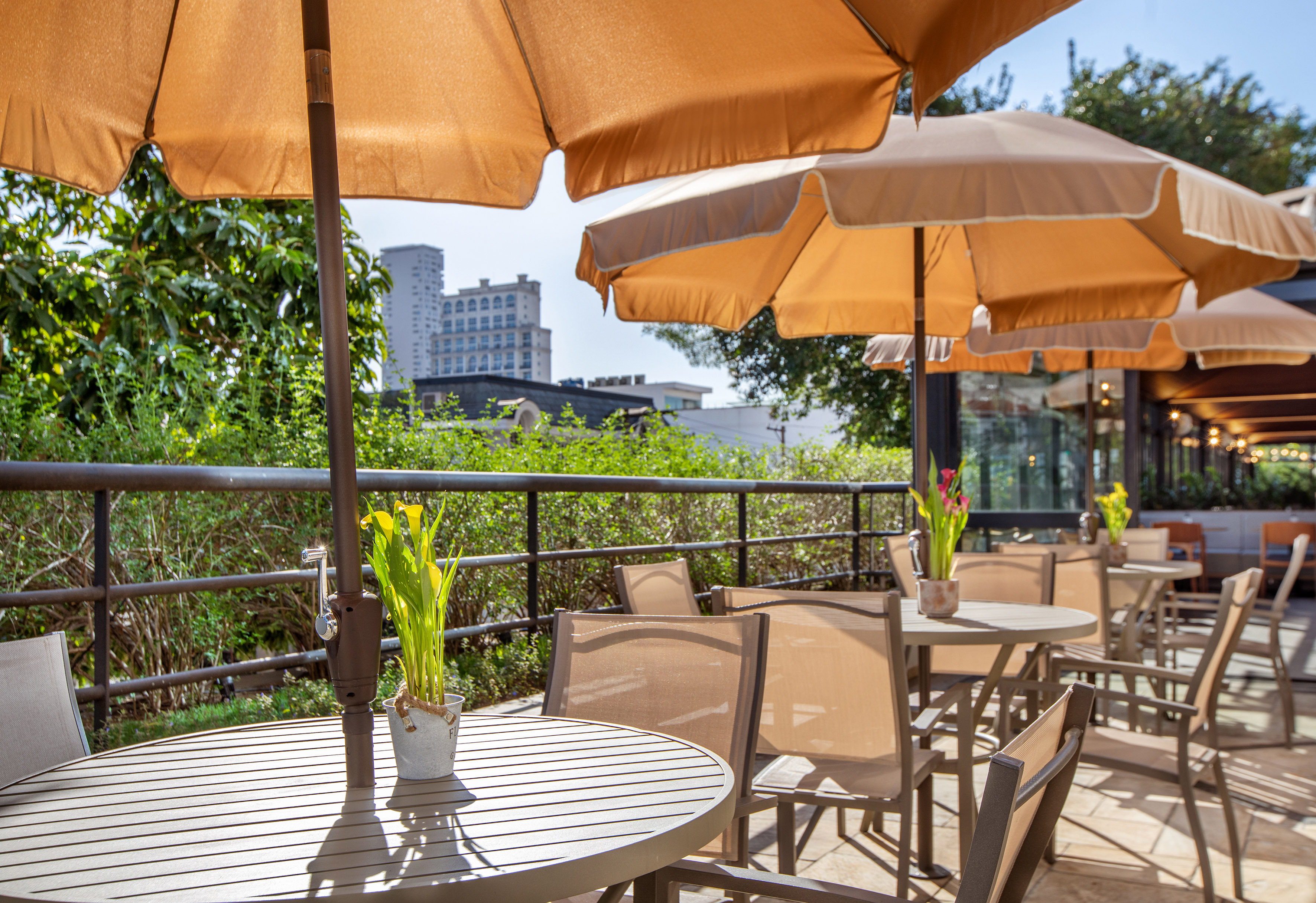 Al fresco dining patio with tables, chairs, and large sun umbrellas.