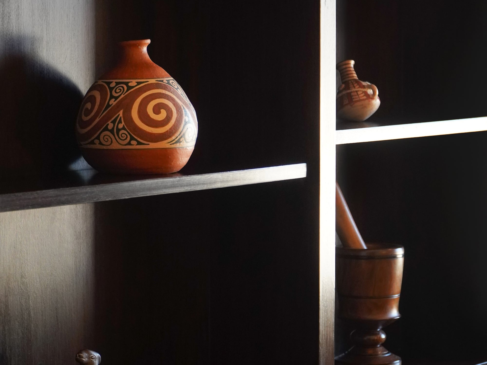 a shelf with a vase and mortar