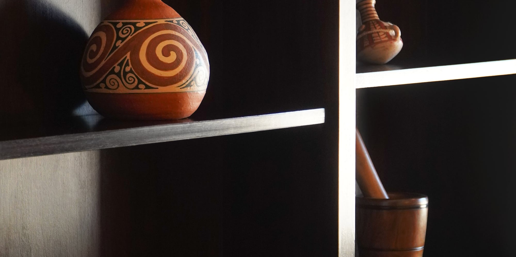 a shelf with a vase and mortar