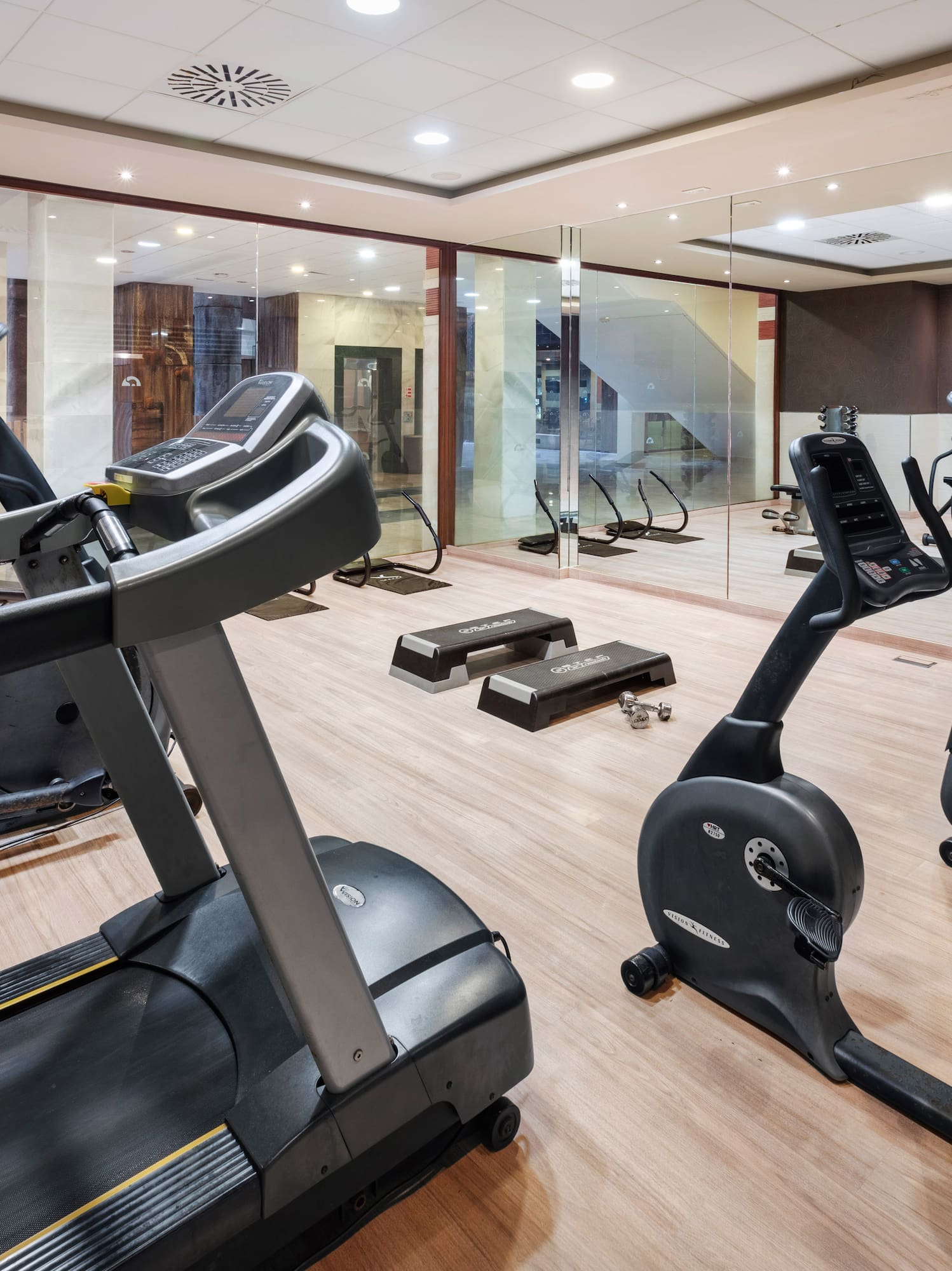 Hotel fitness center with treadmill, elliptical, stationary bikes, and dumbbells.