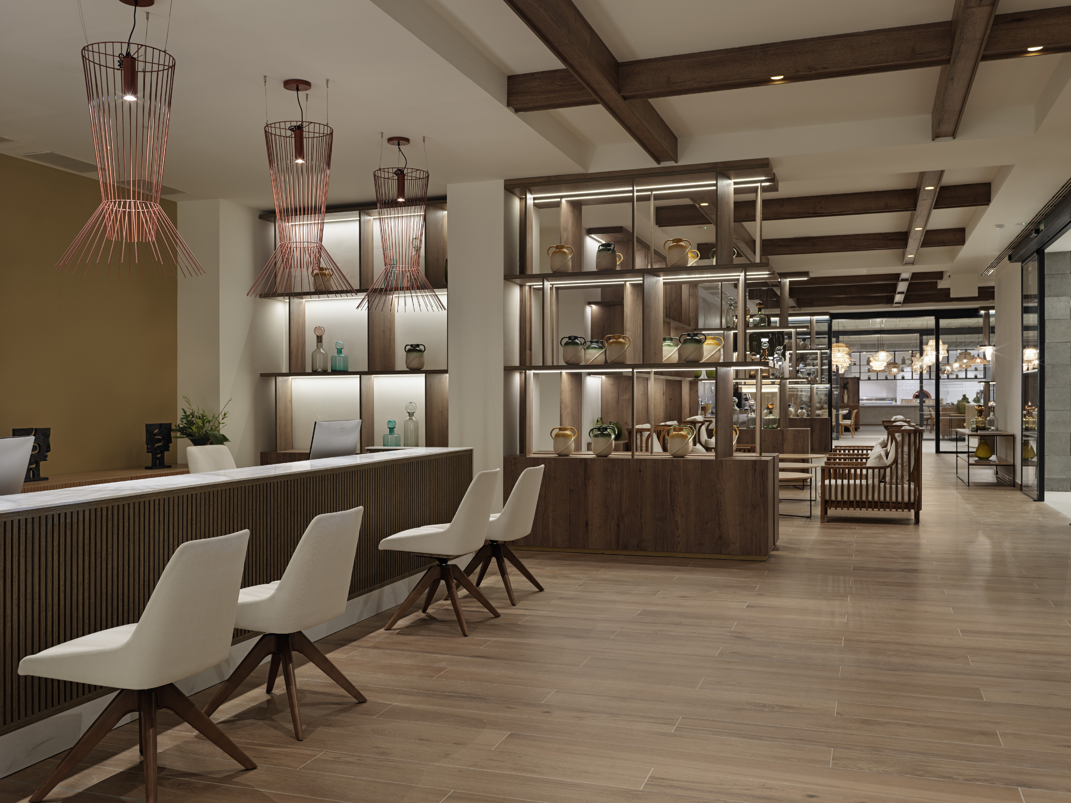 Modern hotel lobby with reception, illuminated shelves, and unique pendant lights.