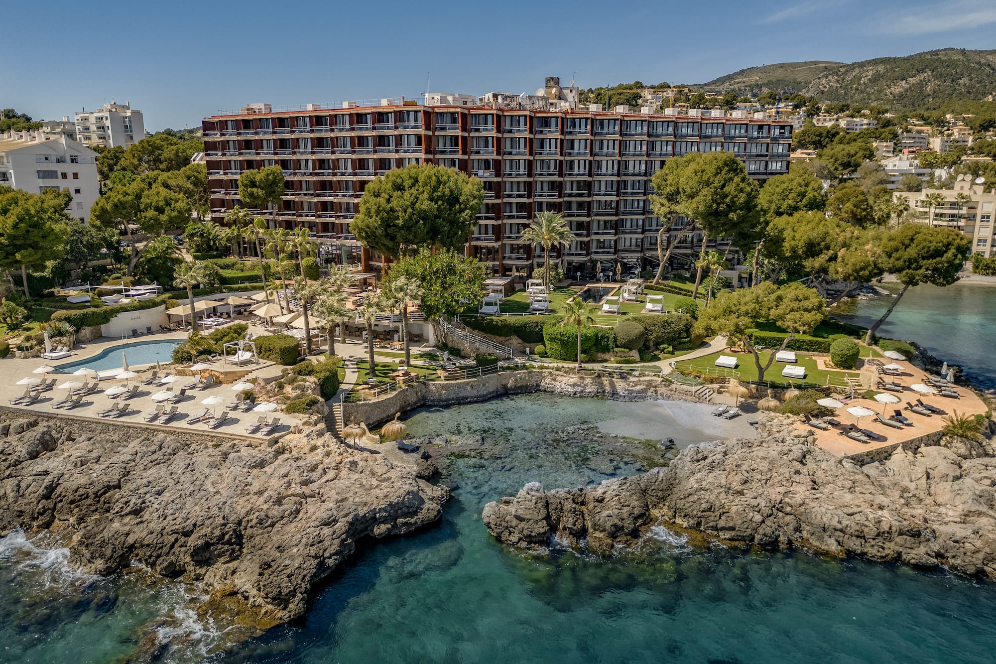 Luxury coastal resort hotel with pools, private beach, and clear sea.