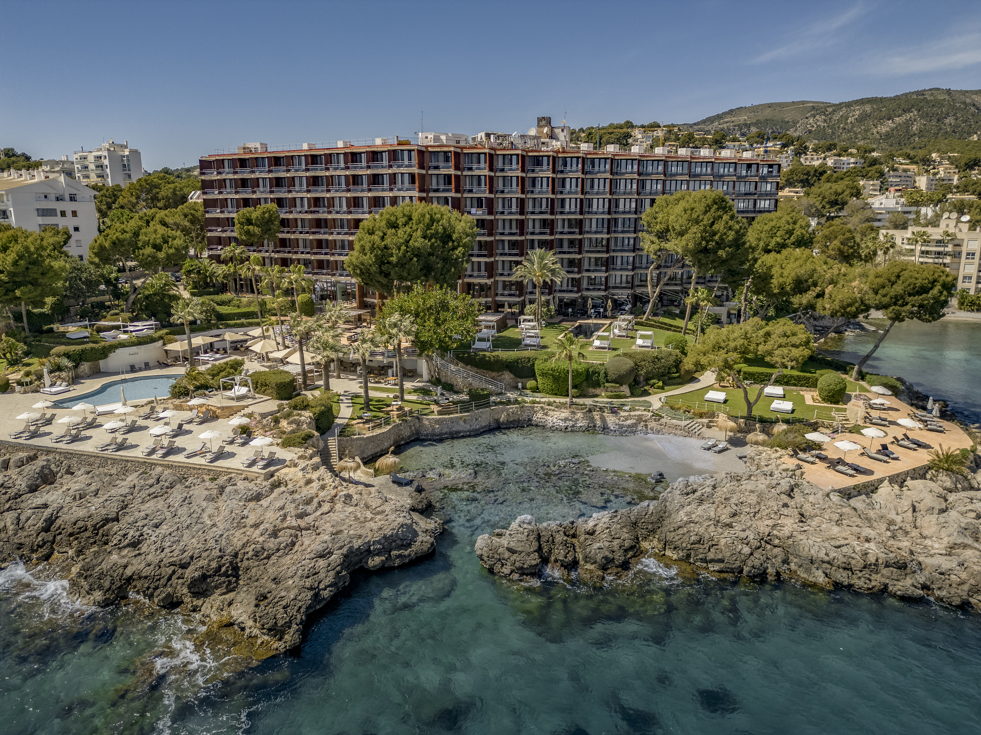 Luxury coastal resort hotel with pools, private beach, and clear sea.