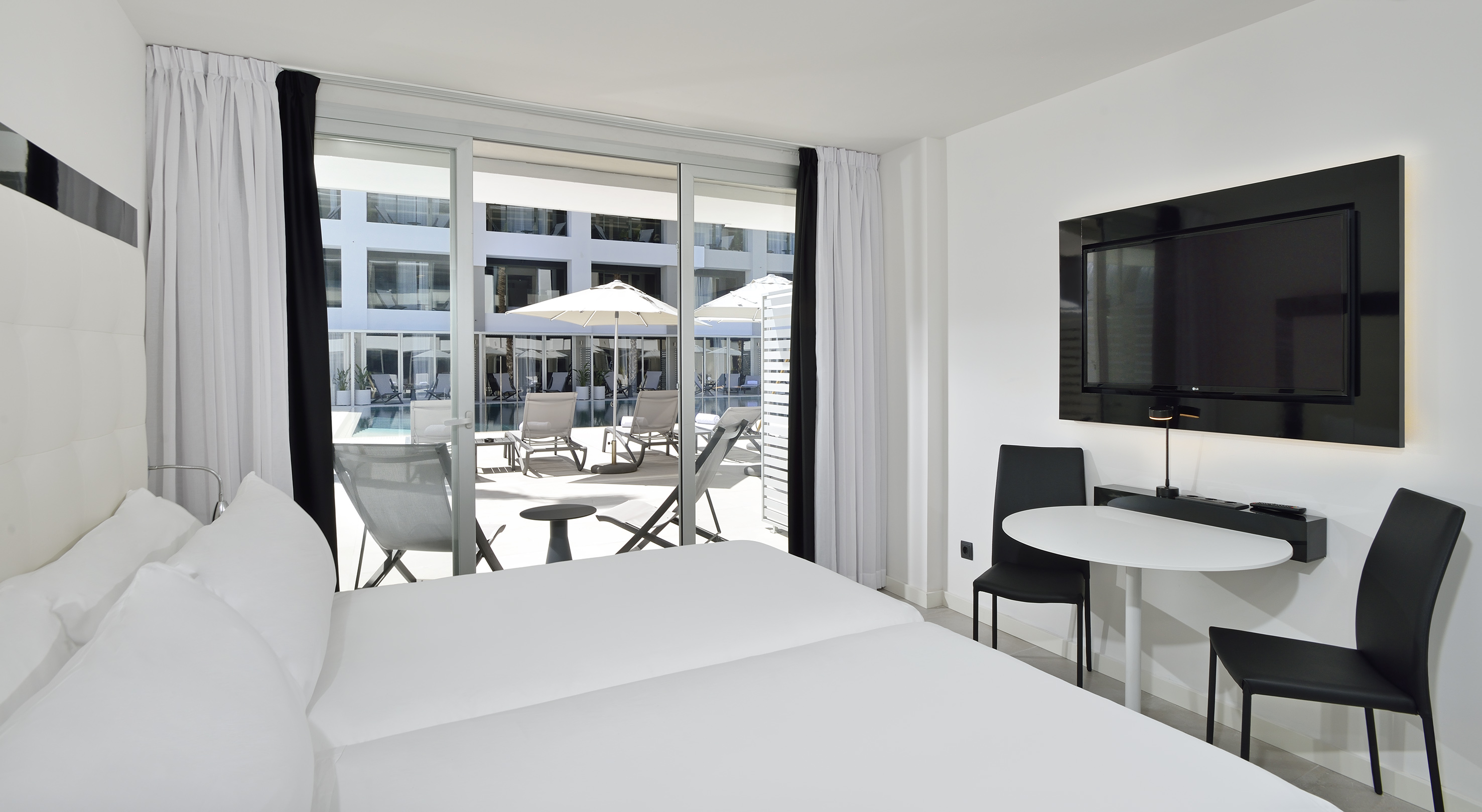 Sleek hotel room with twin beds, private patio, and resort pool view.