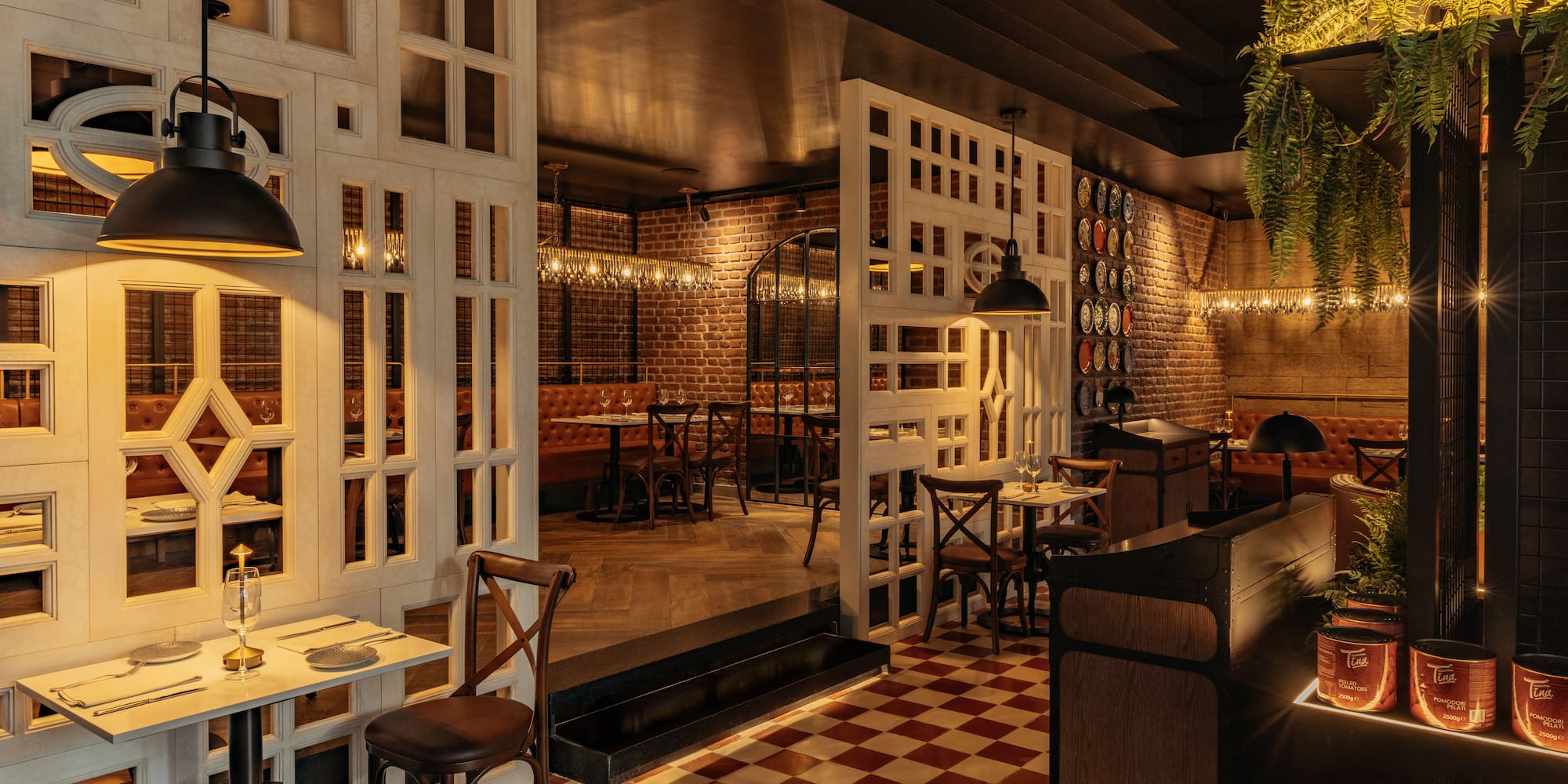 Cozy restaurant interior with brick walls, checkered floor, leather booths, and industrial lighting.