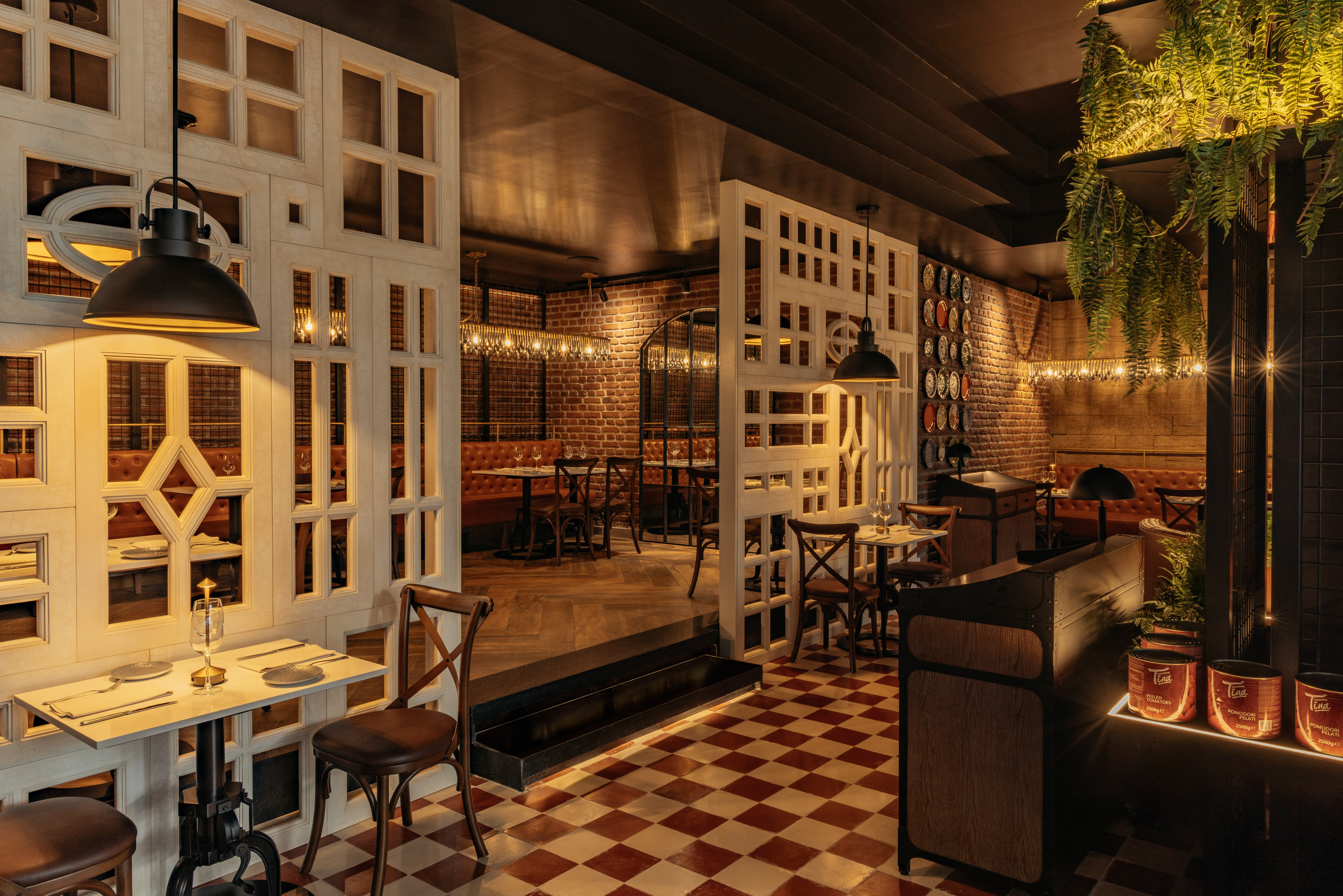Cozy restaurant interior with brick walls, checkered floor, leather booths, and industrial lighting.