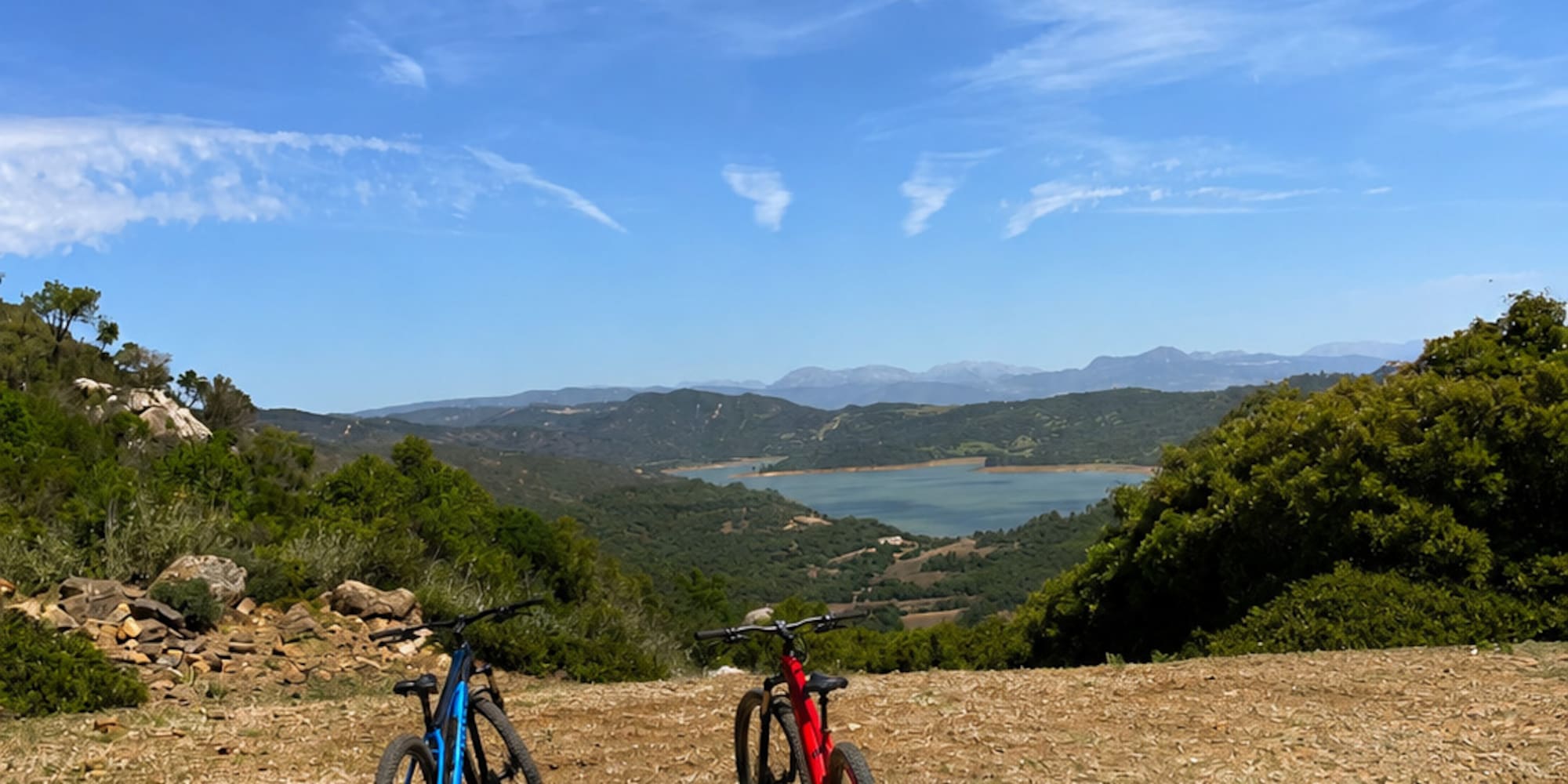 Two mountain bikes overlooking a scenic lake and mountainous landscape.