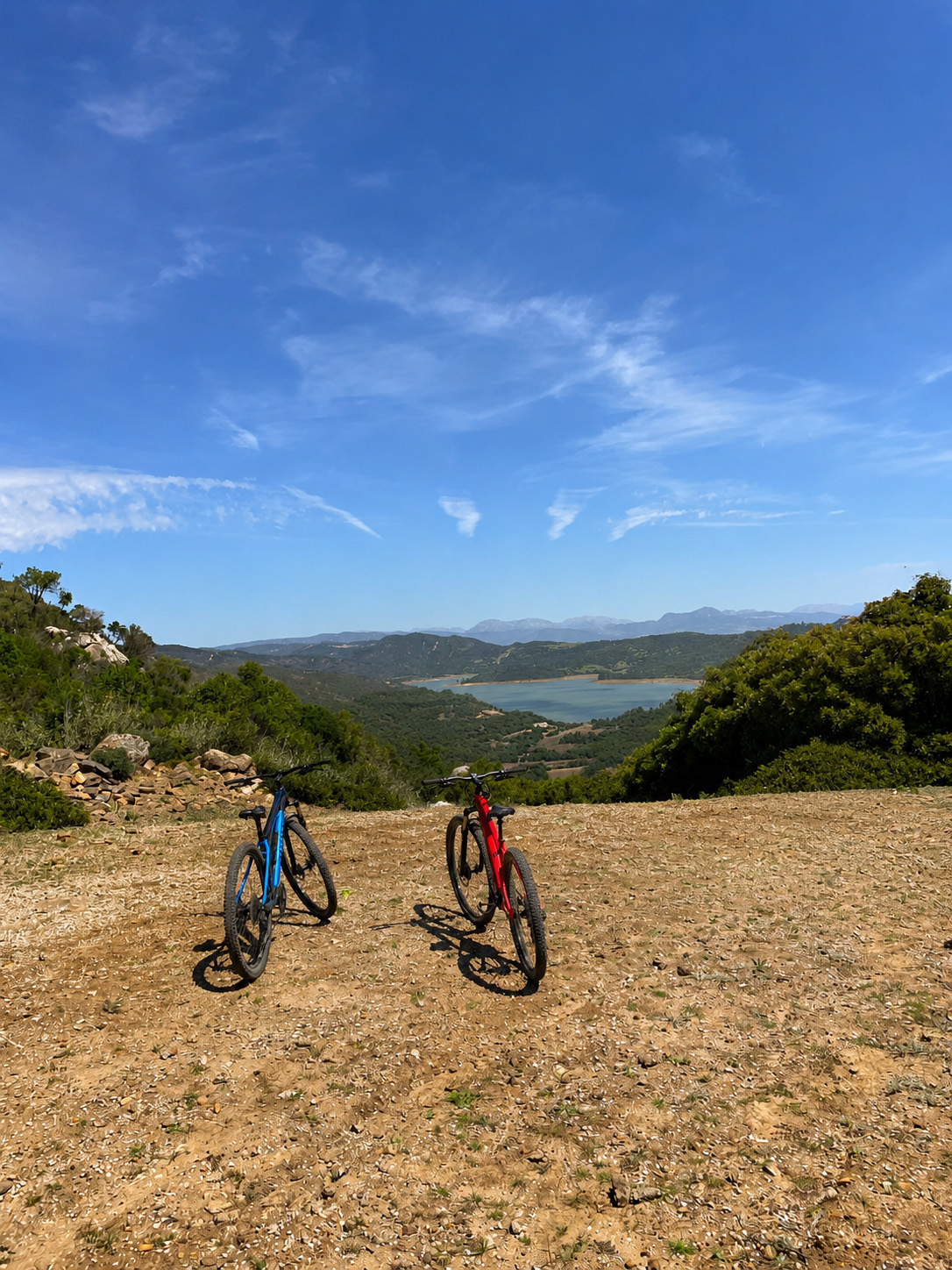 Two mountain bikes overlooking a scenic lake and mountainous landscape.