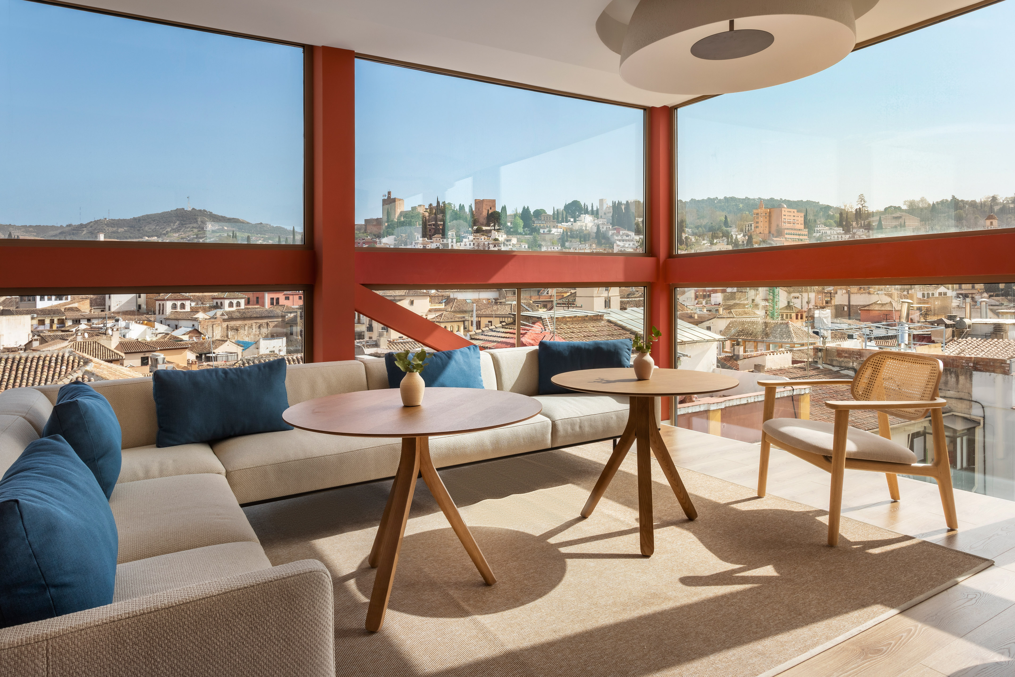 Modern lounge with red frames, panoramic Granada city view, and Alhambra.