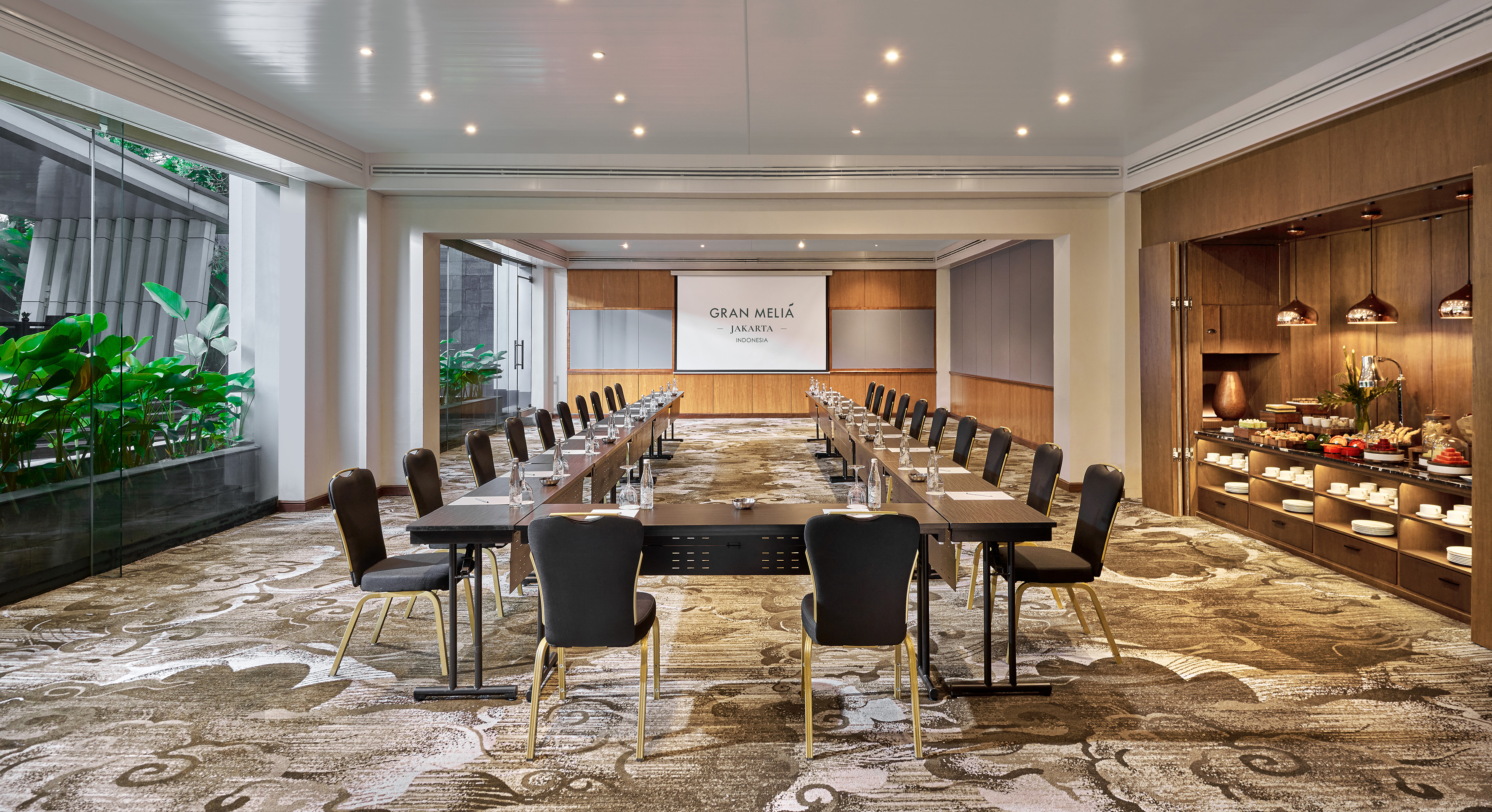 Gran Melia Jakarta conference room with U-shape setup, projector, and buffet.