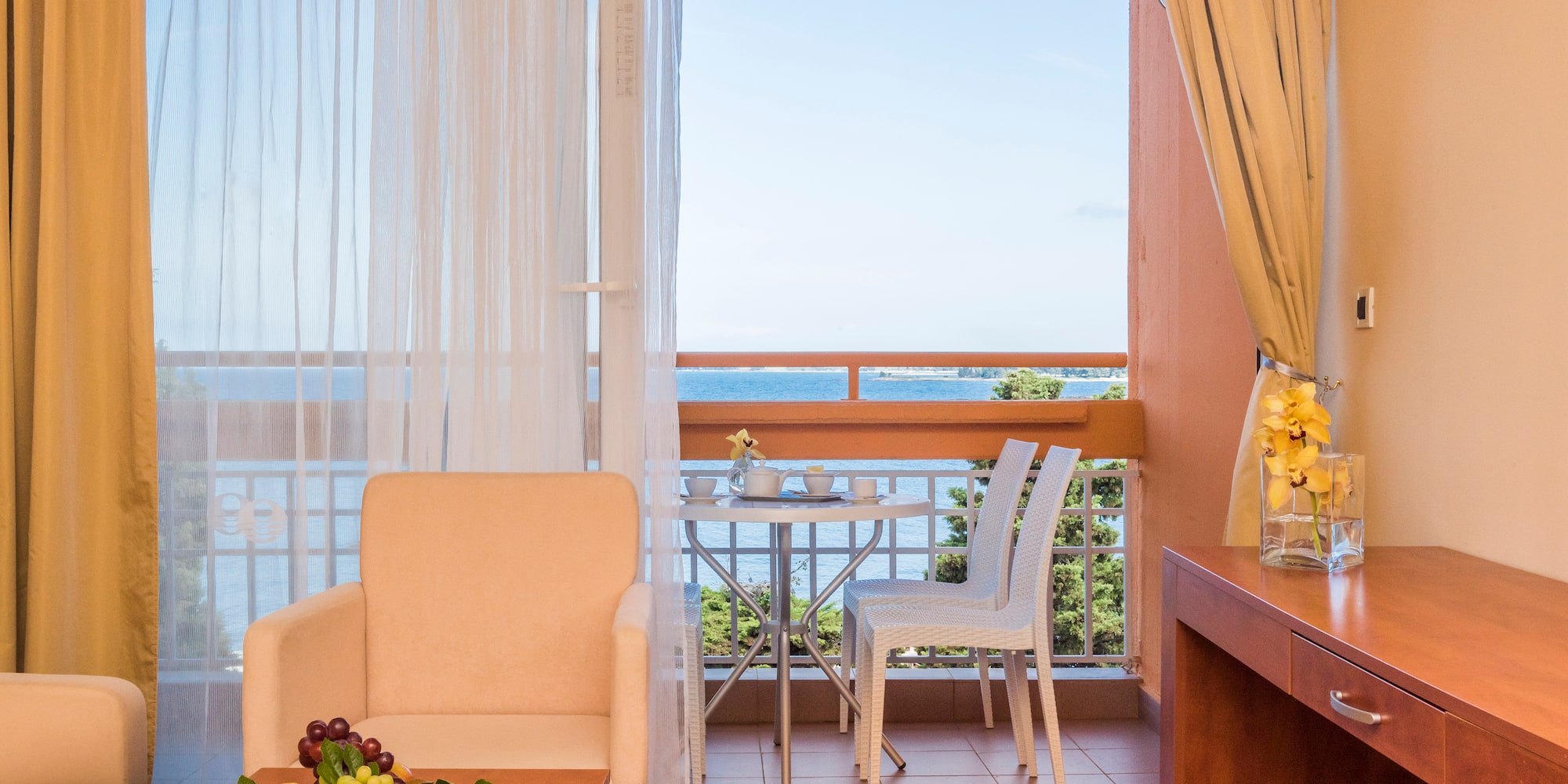 a room with a table and chairs and a table with a view of the ocean
