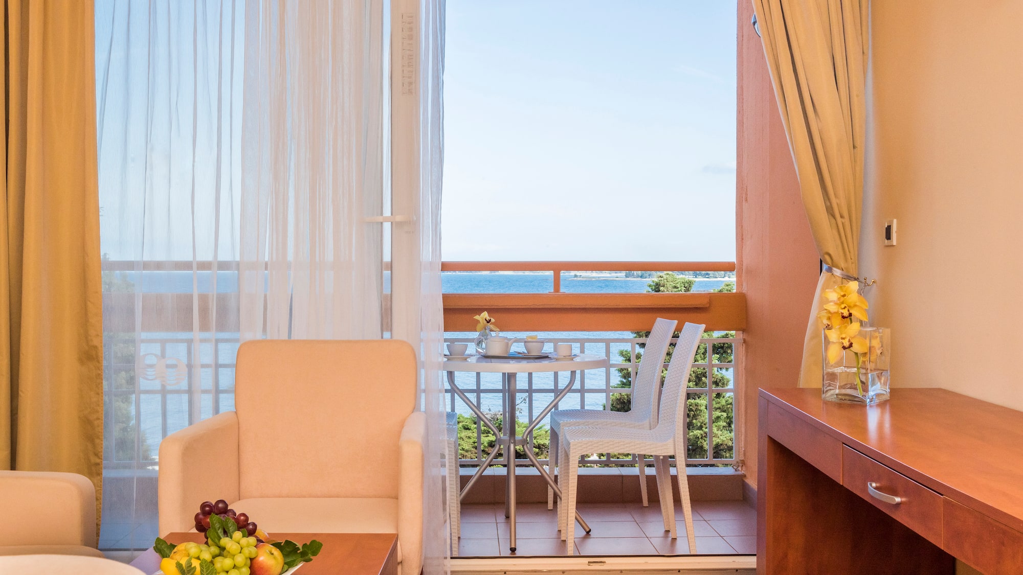 a room with a table and chairs and a table with a view of the ocean