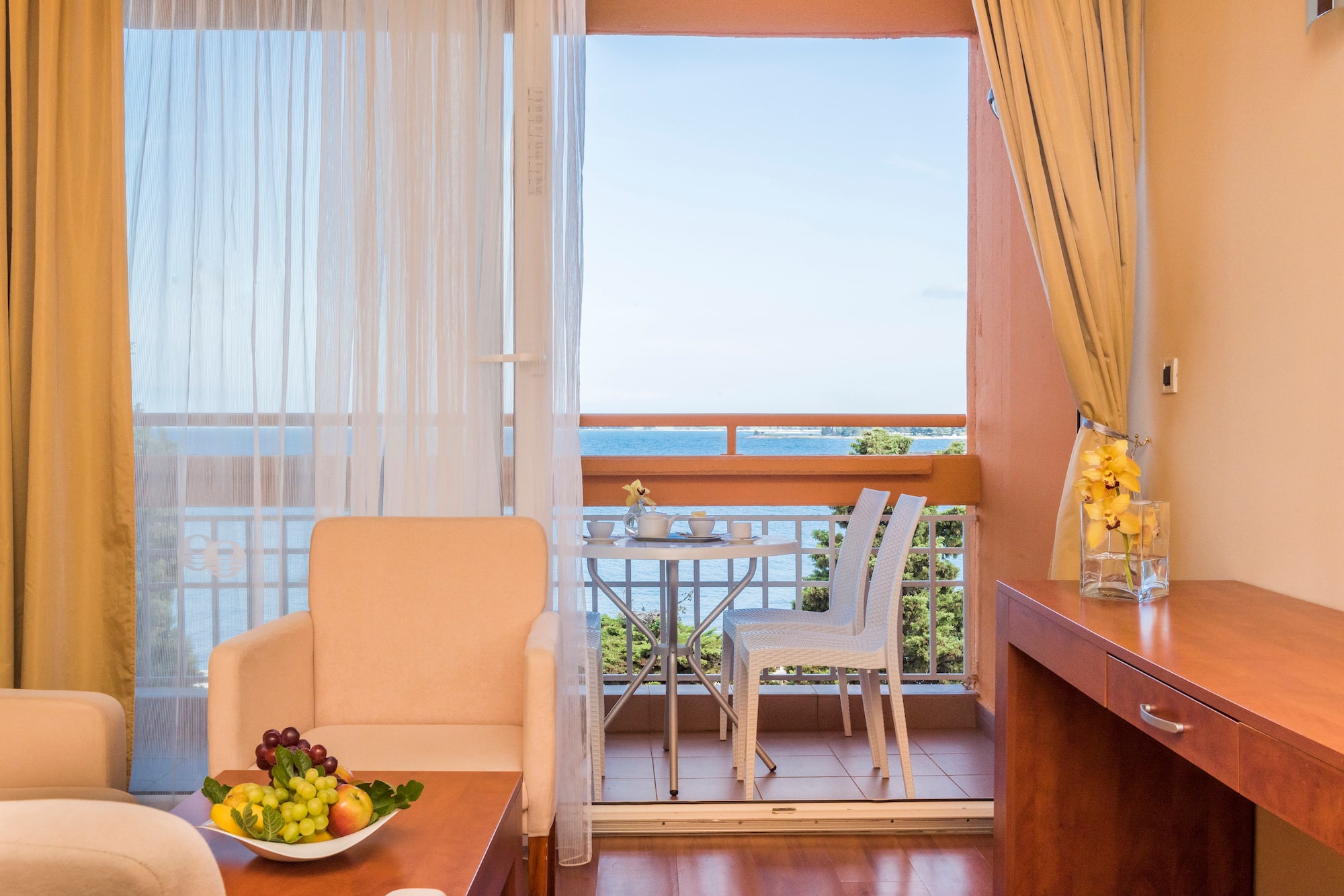 a room with a table and chairs and a table with a view of the ocean