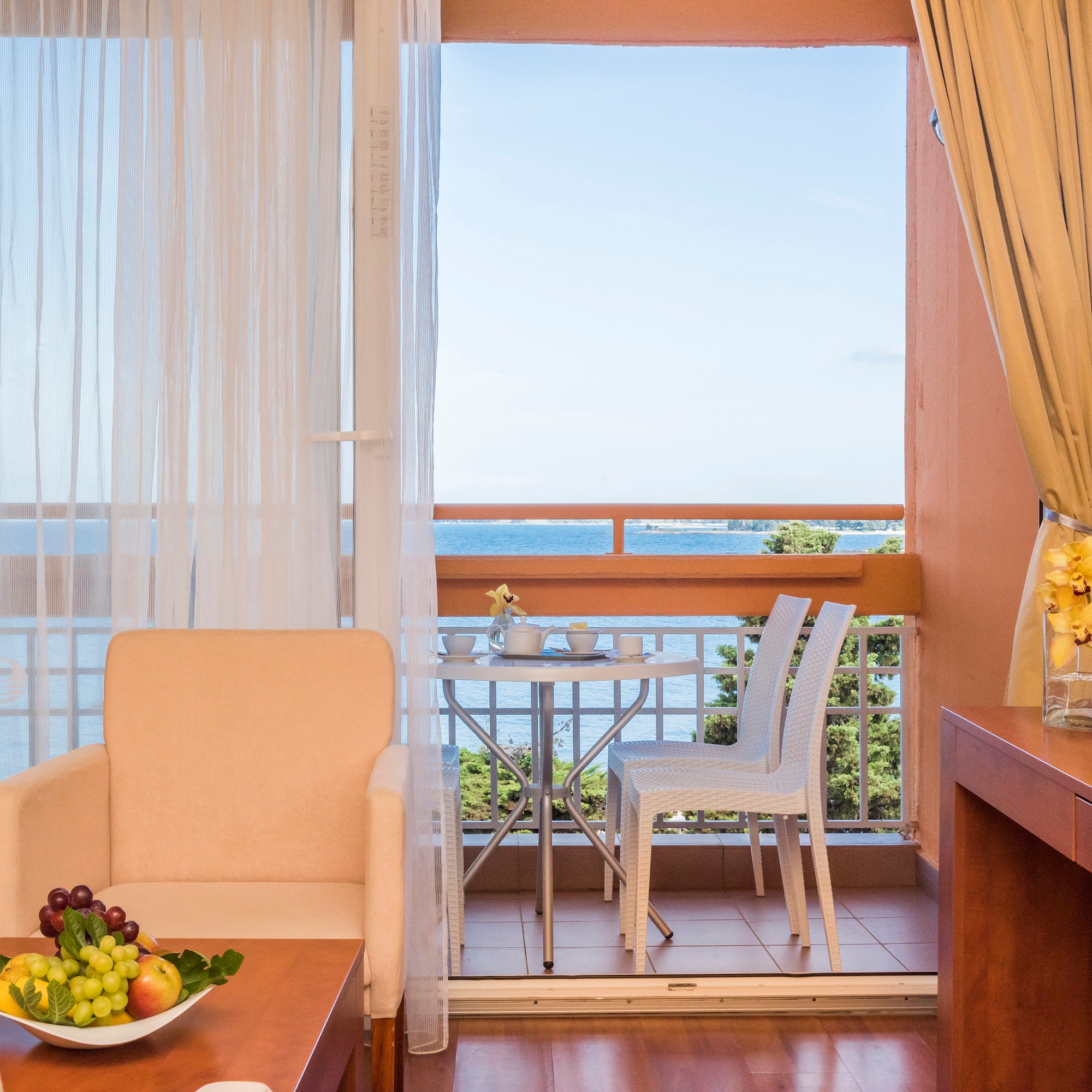 a room with a table and chairs and a table with a view of the ocean