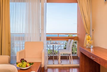 a room with a table and chairs and a table with a view of the ocean