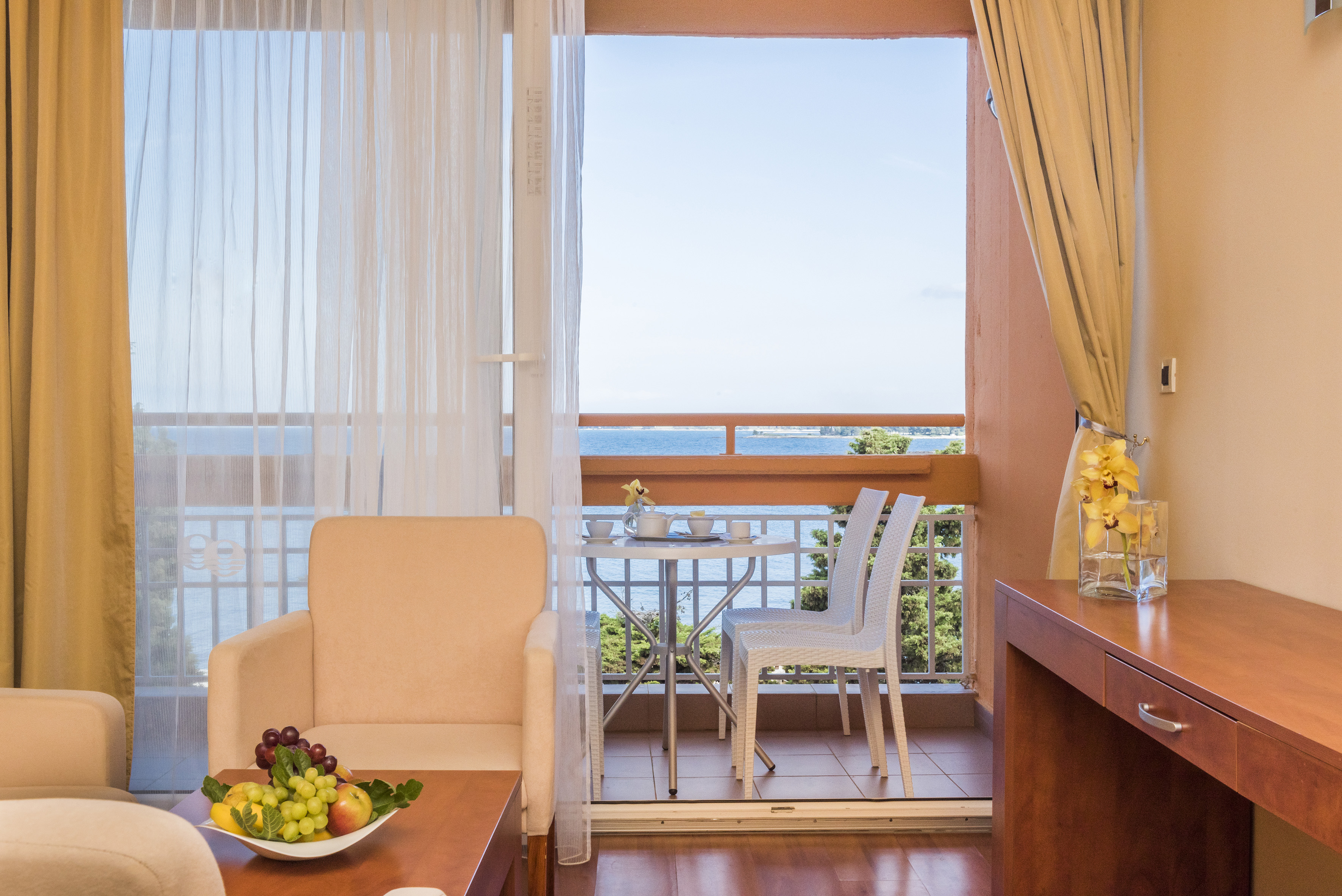 a room with a table and chairs and a table with a view of the ocean