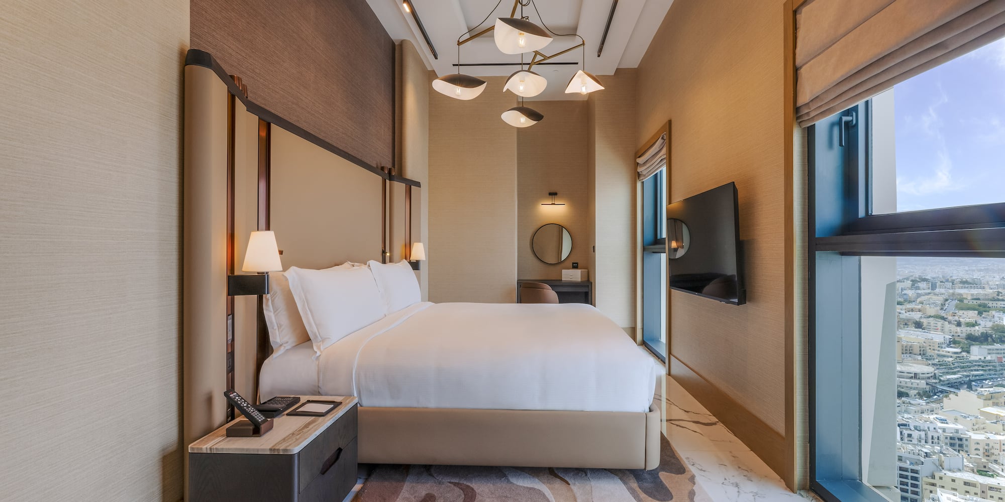 Luxury modern hotel bedroom with king bed and city view.