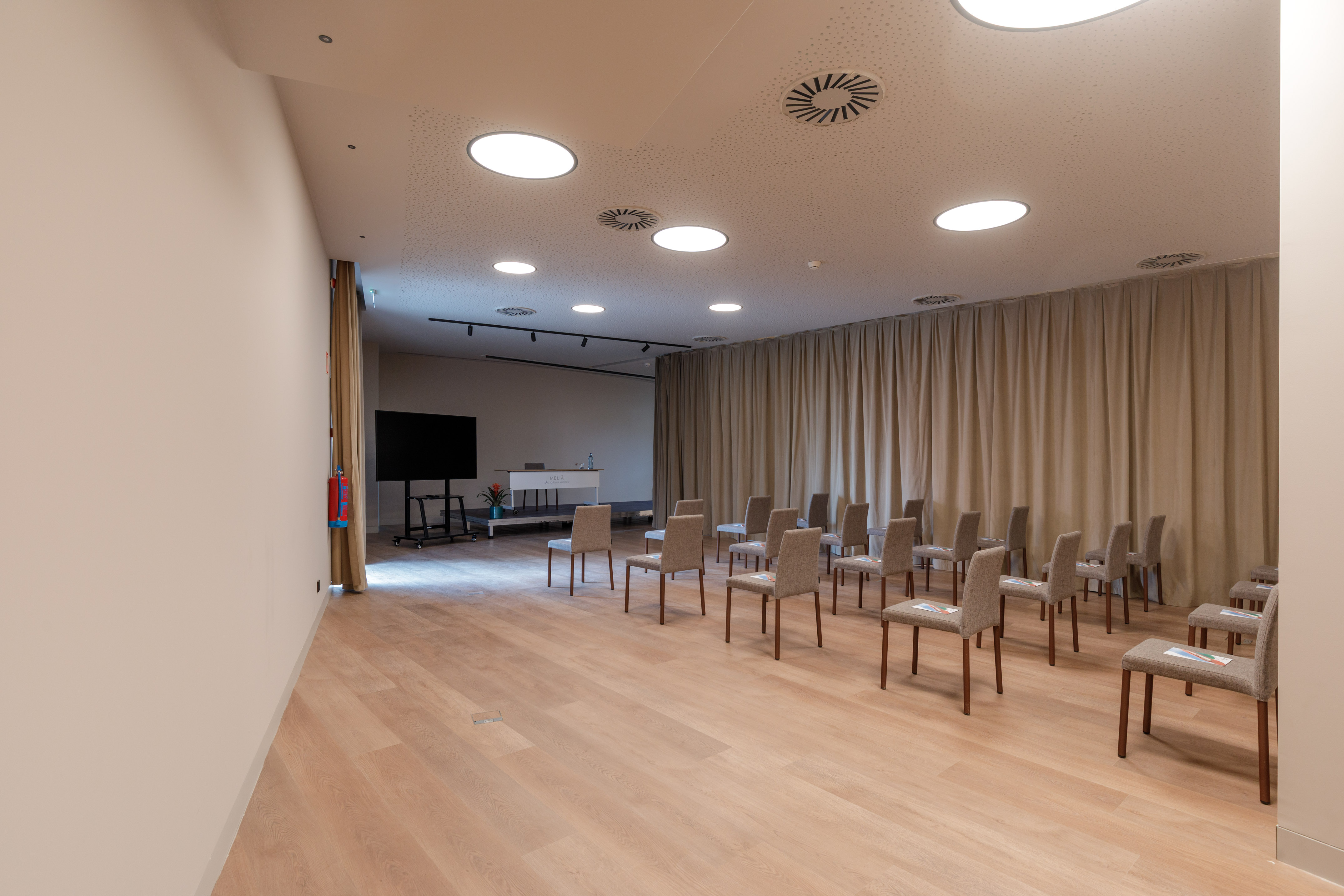Modern corporate event space with rows of chairs and presentation screen.