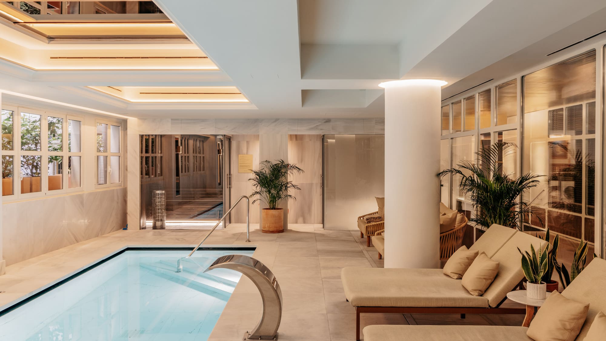 Spa de lujo con piscina interior, tumbonas y plantas.