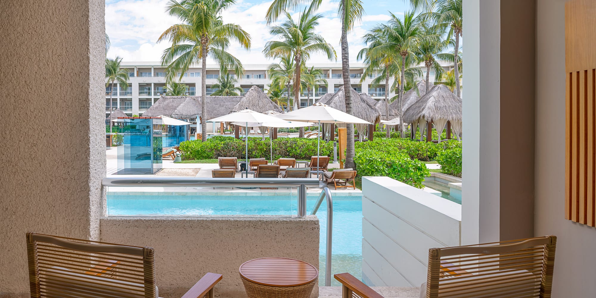 Luxury resort patio with swim-out pool, palm trees, and resort pool area.