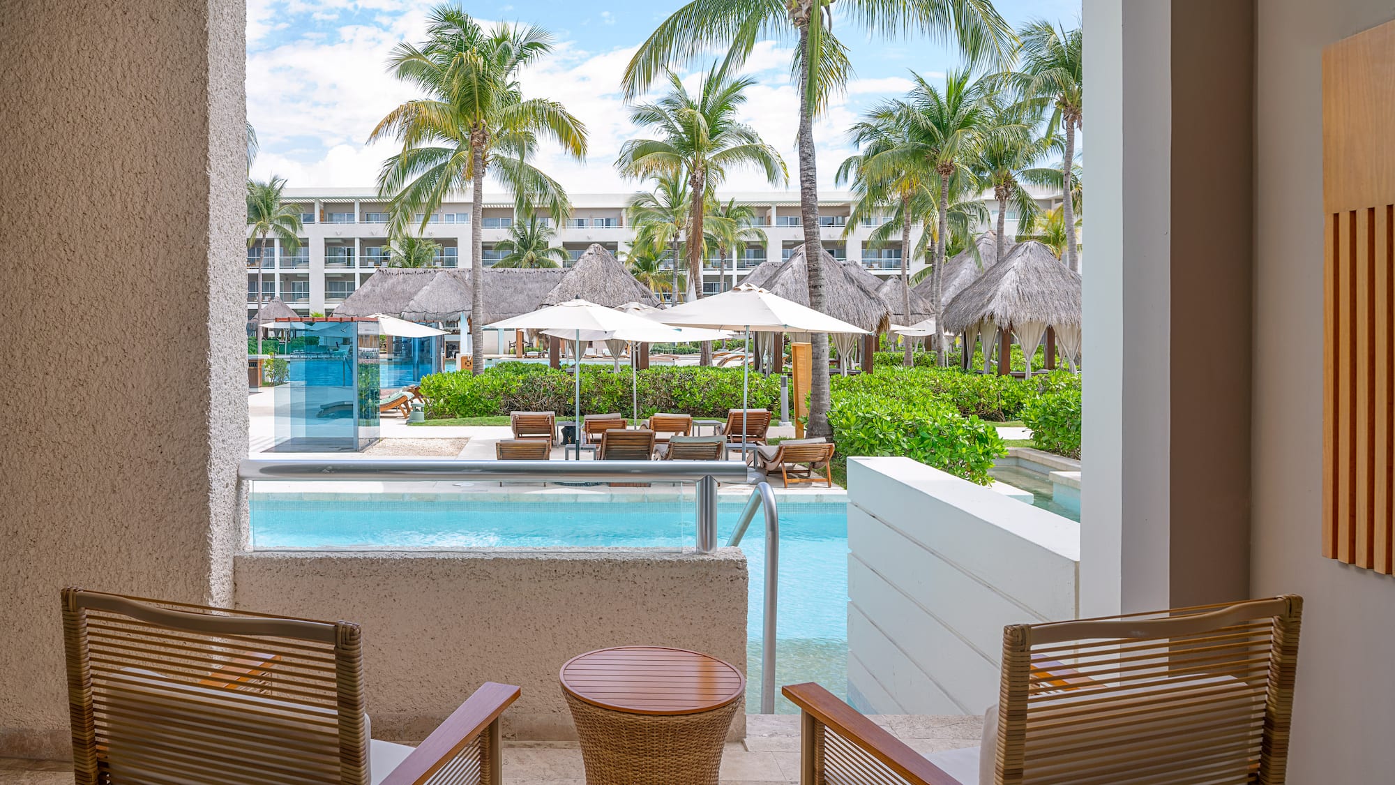 Luxury resort patio with swim-out pool, palm trees, and resort pool area.