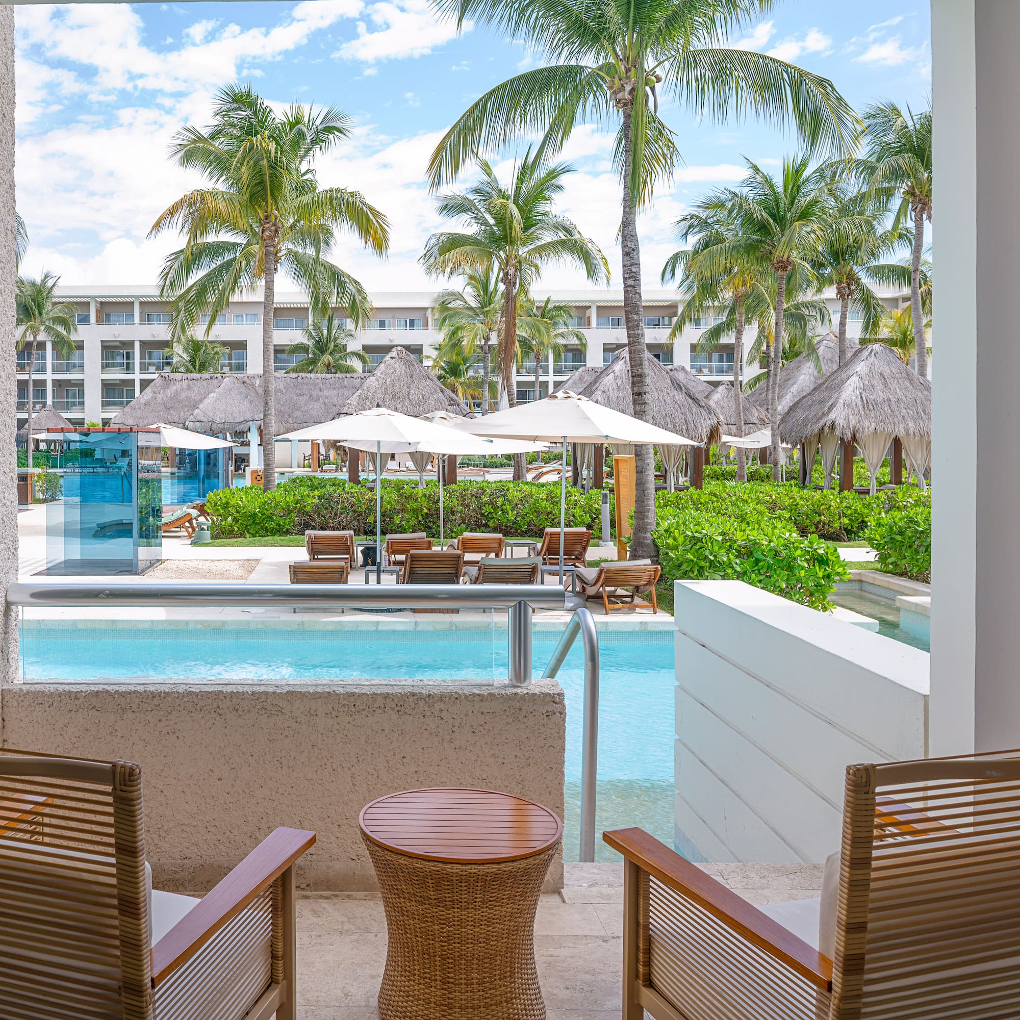 Luxury resort patio with swim-out pool, palm trees, and resort pool area.