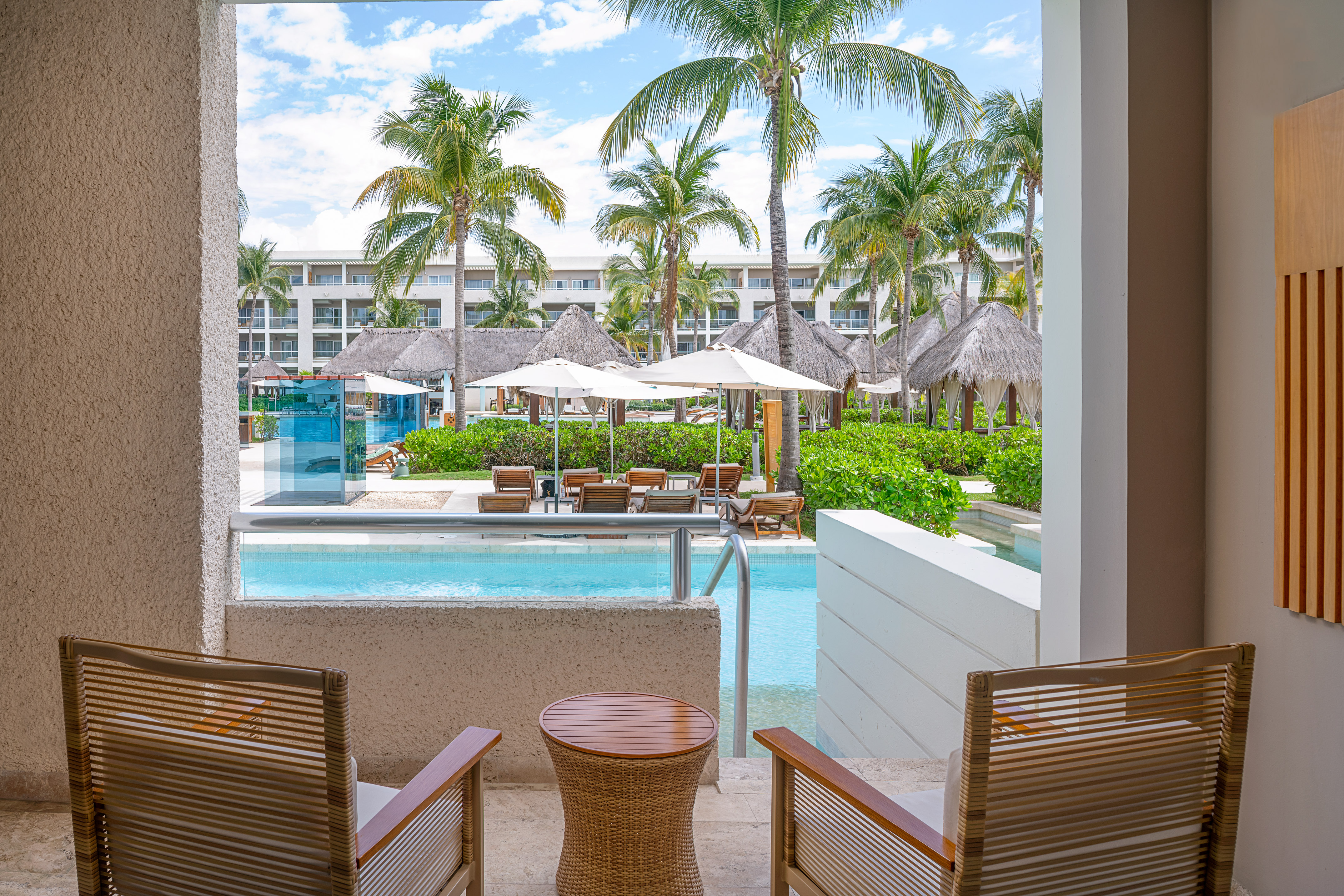 Luxury resort patio with swim-out pool, palm trees, and resort pool area.