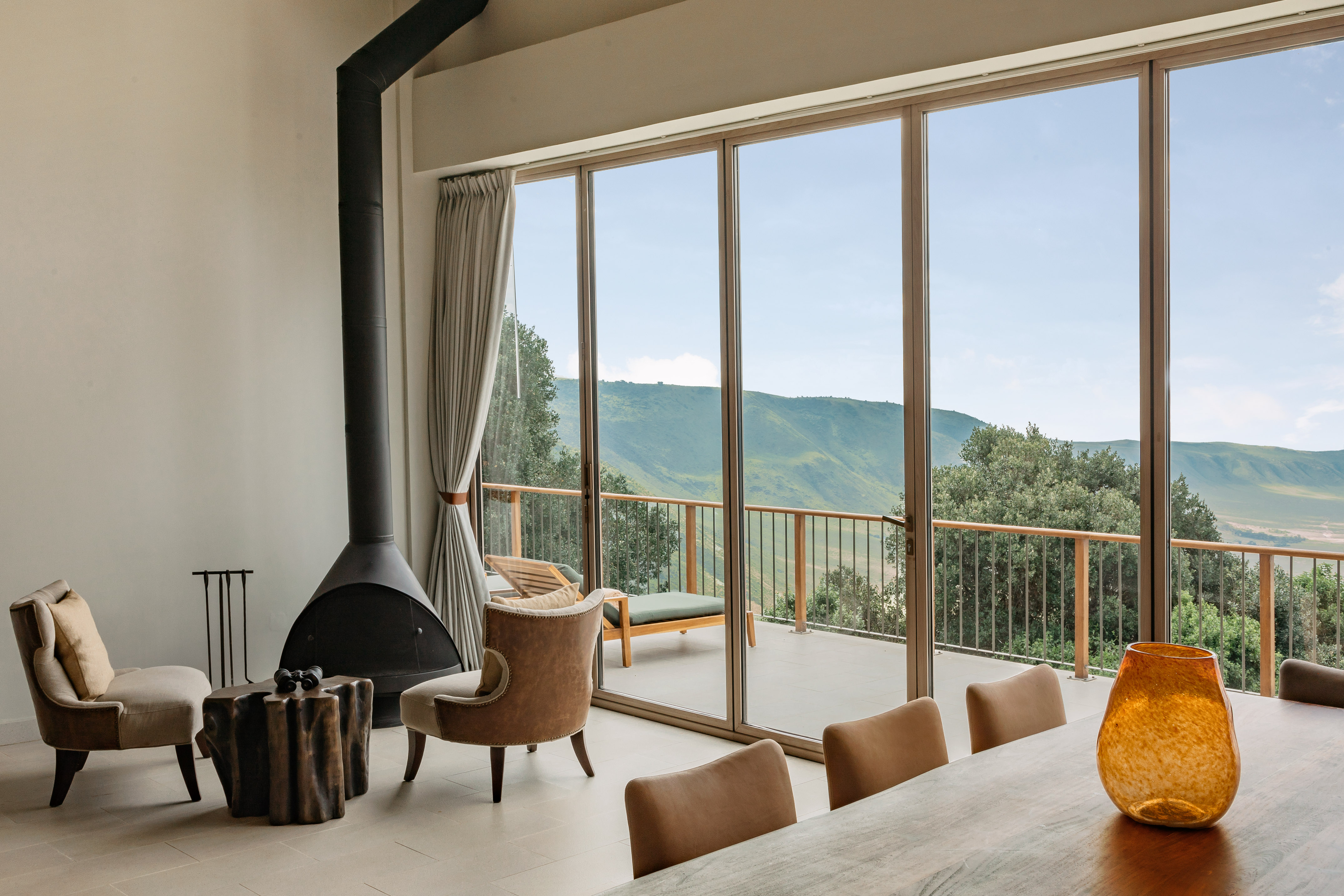 Safari lodge interior with fireplace and panoramic crater views.