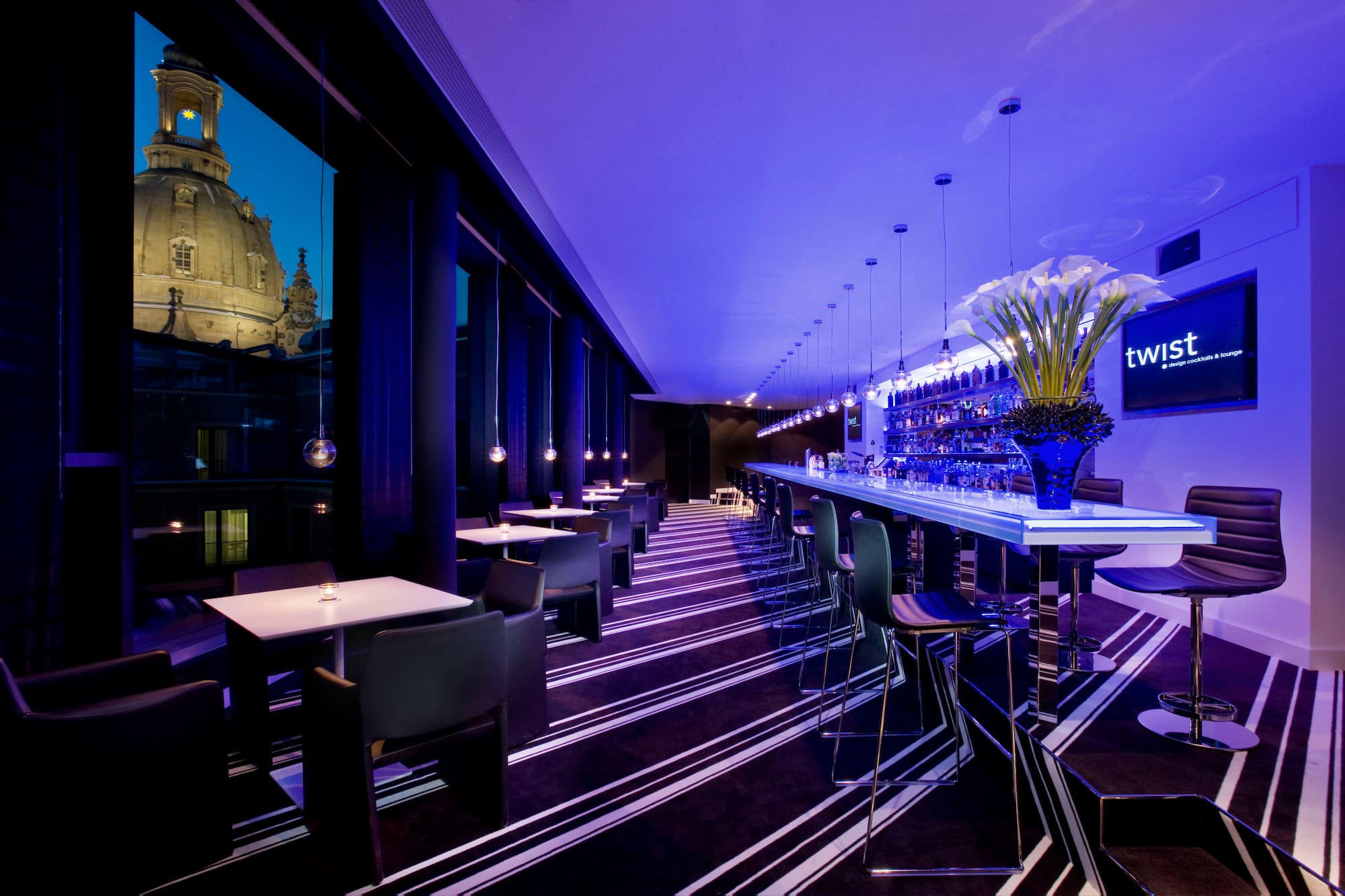 Modern cocktail lounge with blue lighting, Dresden Frauenkirche dome view.